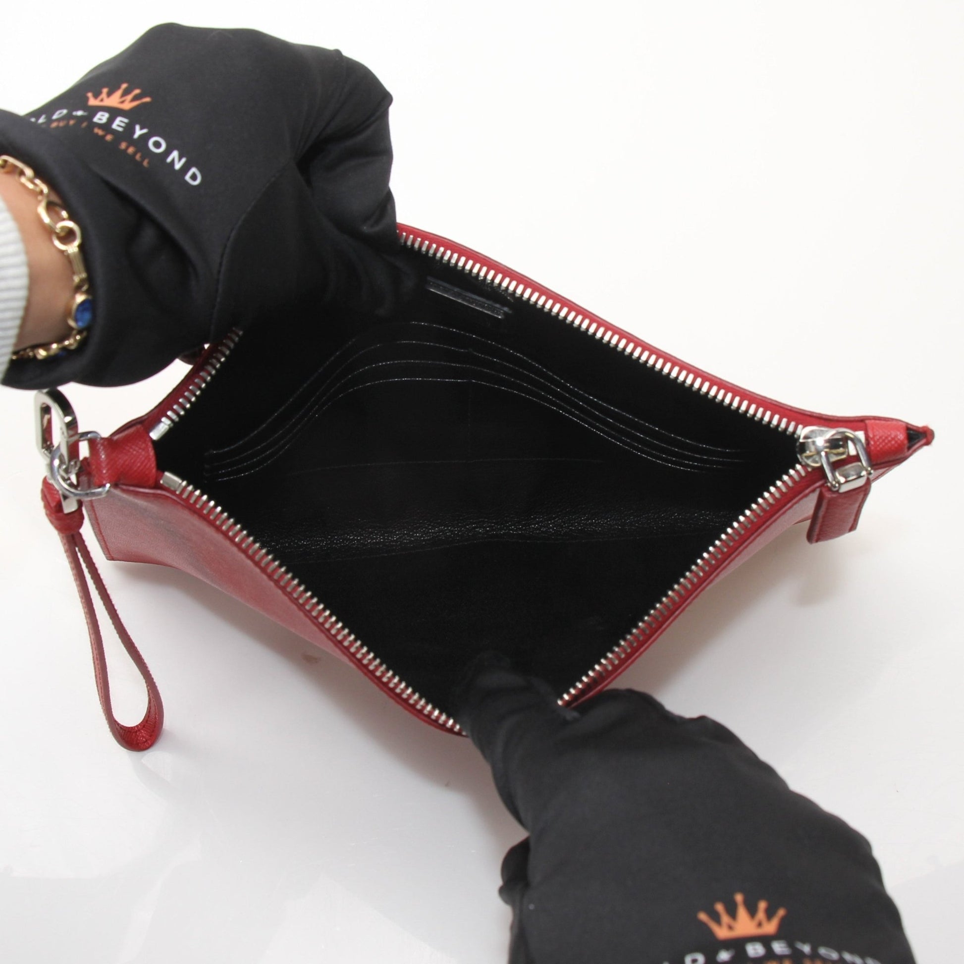 Red Prada Saffiano leather wristlet pouch with gold hardware, featuring a compact handbag design and wrist strap.