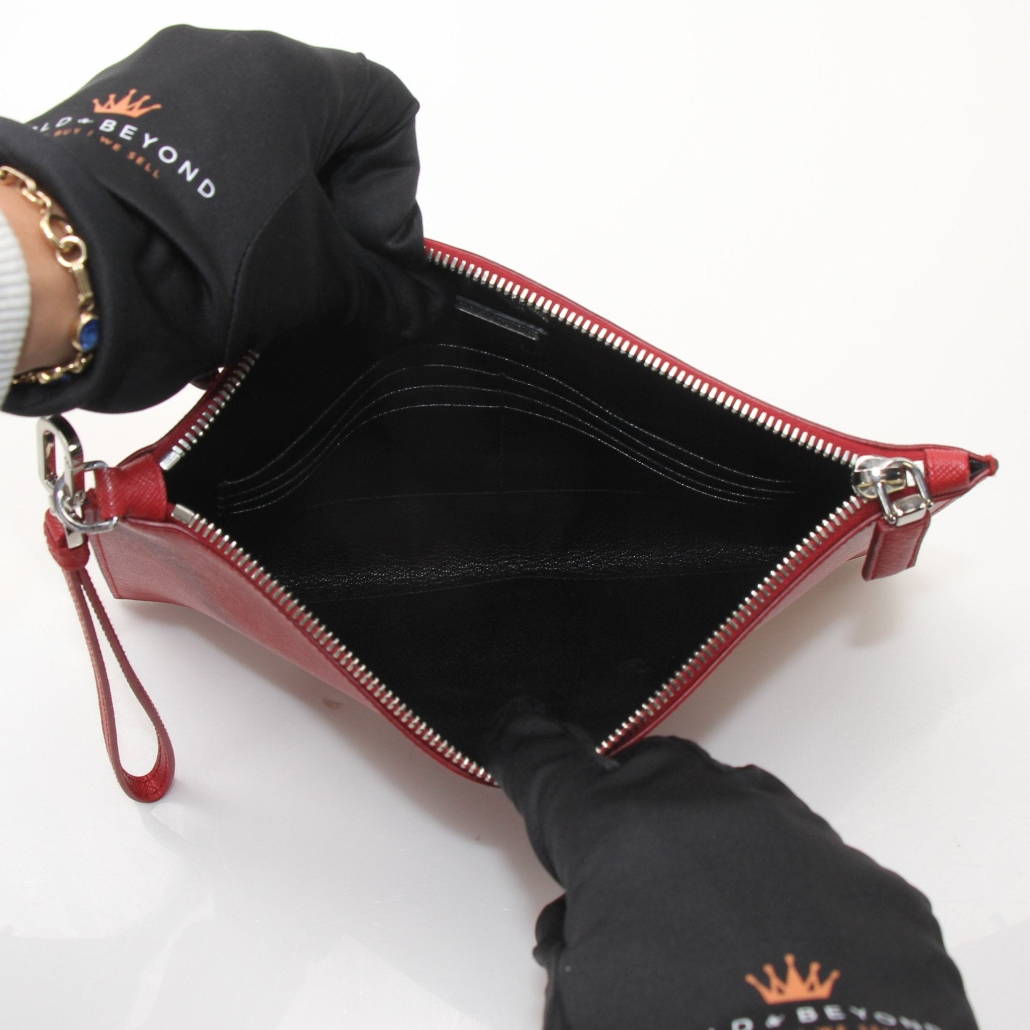 Red Prada Saffiano leather wristlet pouch with gold hardware, featuring a compact handbag design and wrist strap.
