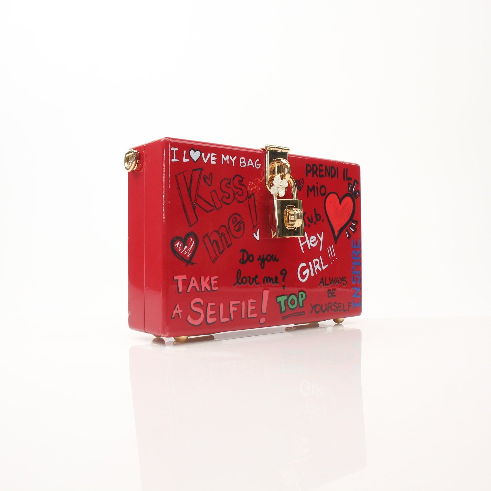 Dolce & Gabbana Red Graffiti Box Clutch handbag with bold graffiti design and gold accents, held in hand.