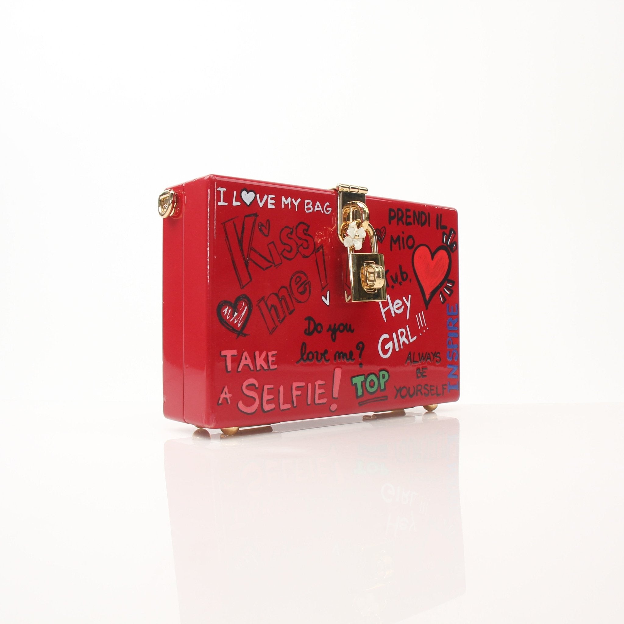 Dolce & Gabbana Red Graffiti Box Clutch handbag with bold graffiti design and gold accents, held in hand.