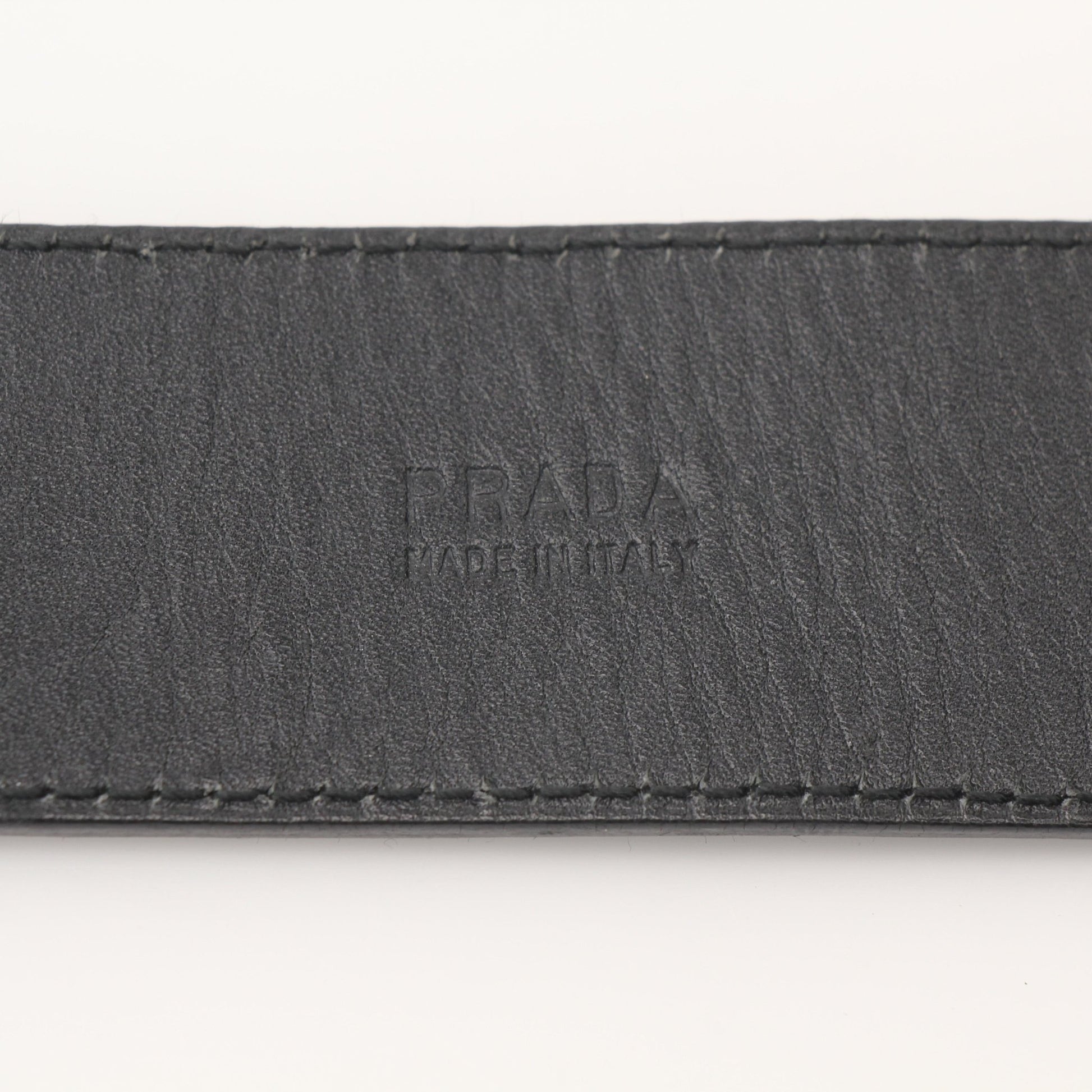 Prada black saffiano leather belt, accessory with a sleek metal buckle, showcasing fine craftsmanship and textured leather.