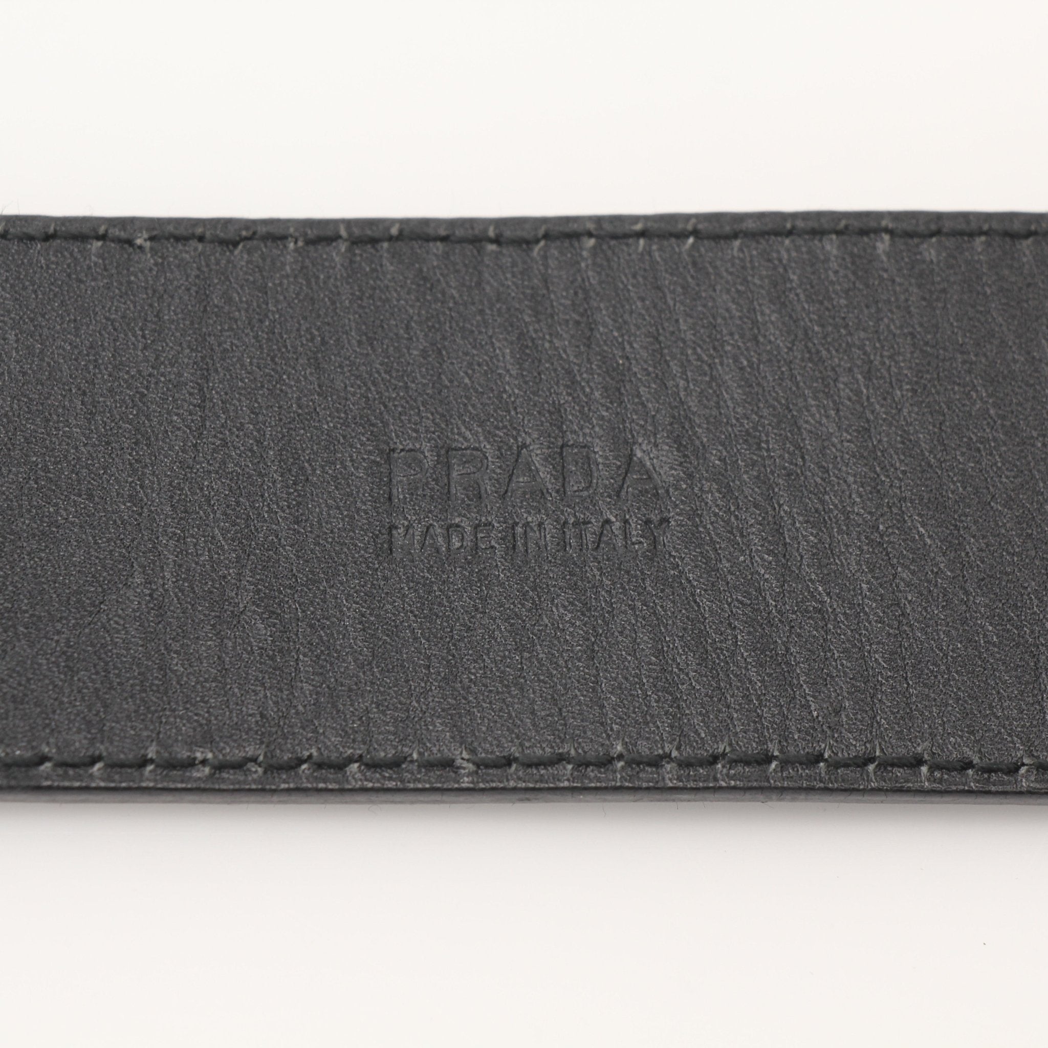 Prada black saffiano leather belt, accessory with a sleek metal buckle, showcasing fine craftsmanship and textured leather.
