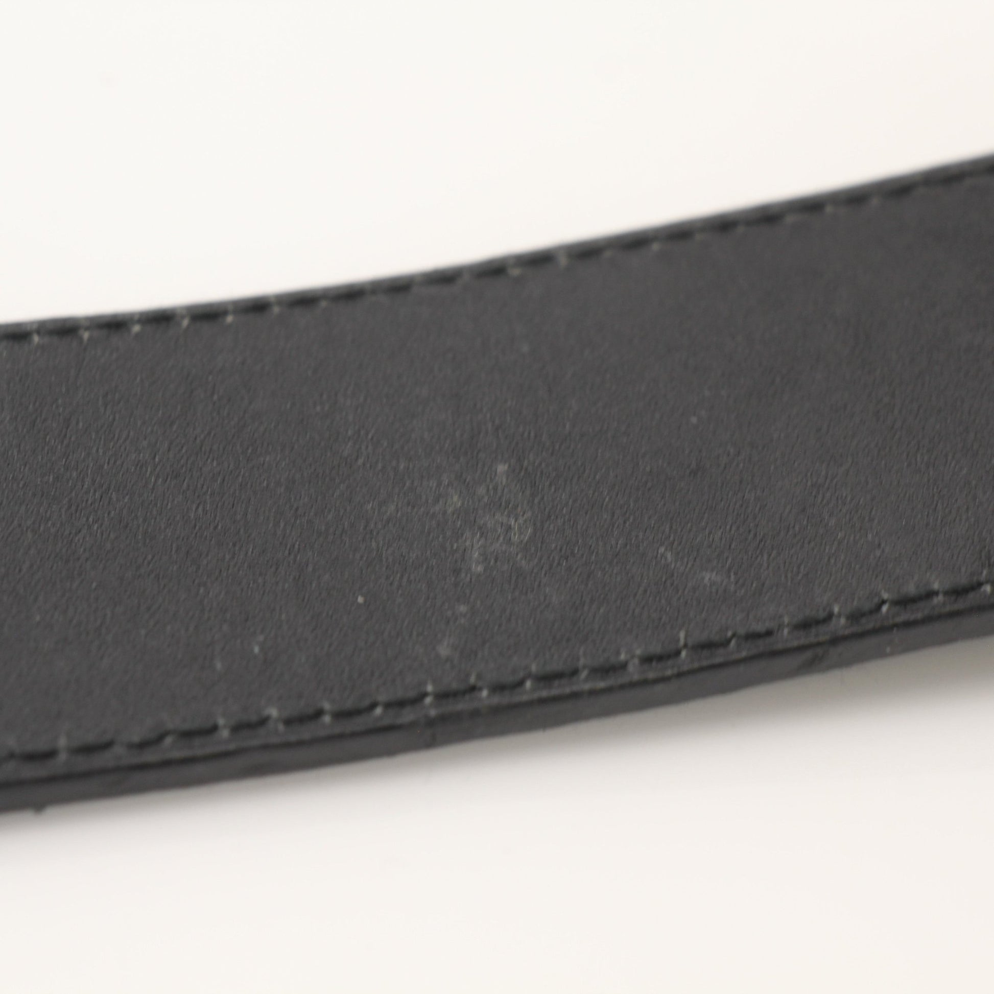 Prada black saffiano leather belt with gold hardware, displayed as a stylish accessory on a plain background.