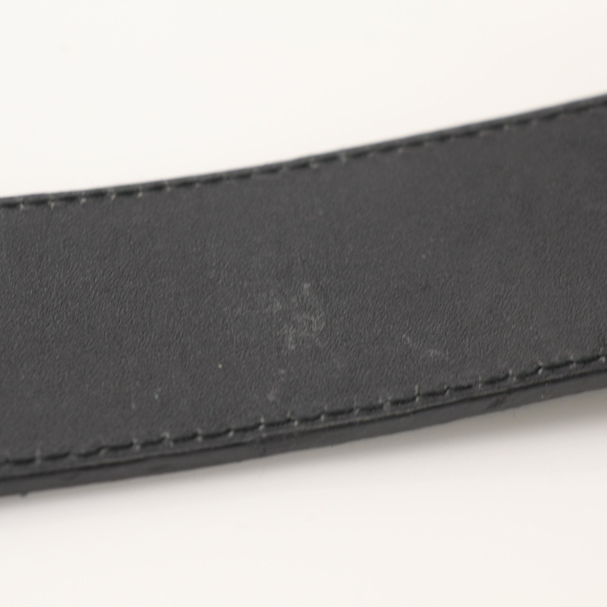 Prada black saffiano leather belt with gold hardware, displayed as a stylish accessory on a plain background.