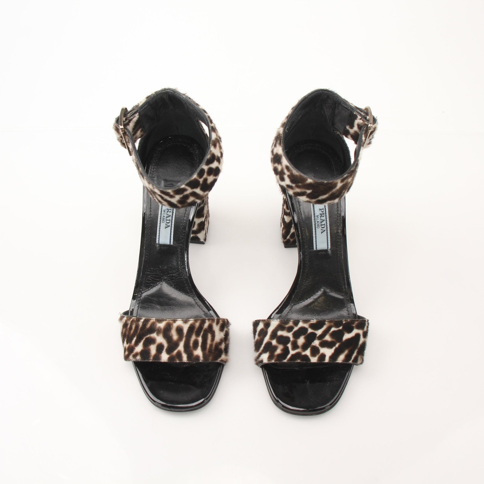 Prada pony hair leopard print block heel sandals with ankle straps and open toes, displayed on a white background.