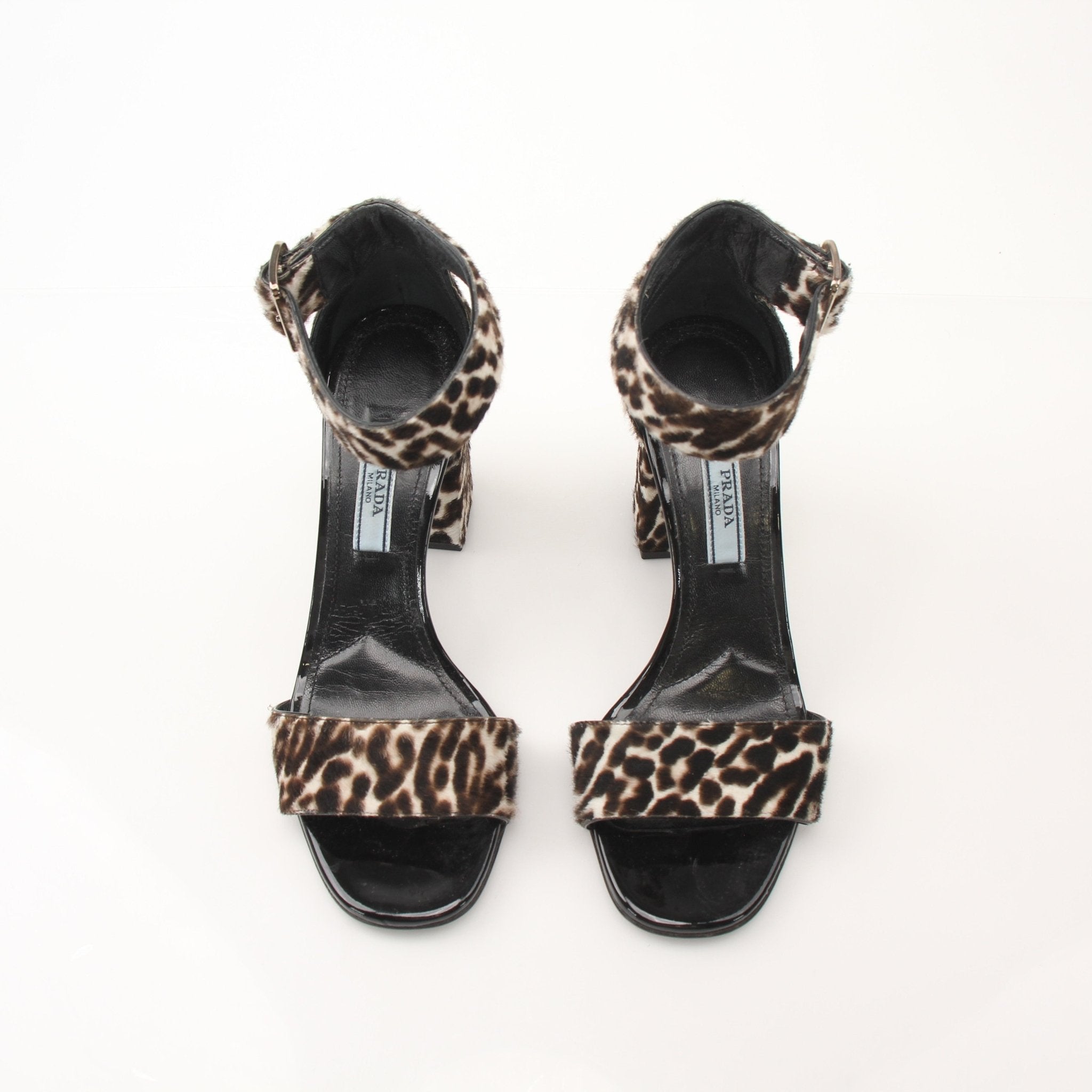 Prada pony hair leopard print block heel sandals with ankle straps and open toes, displayed on a white background.