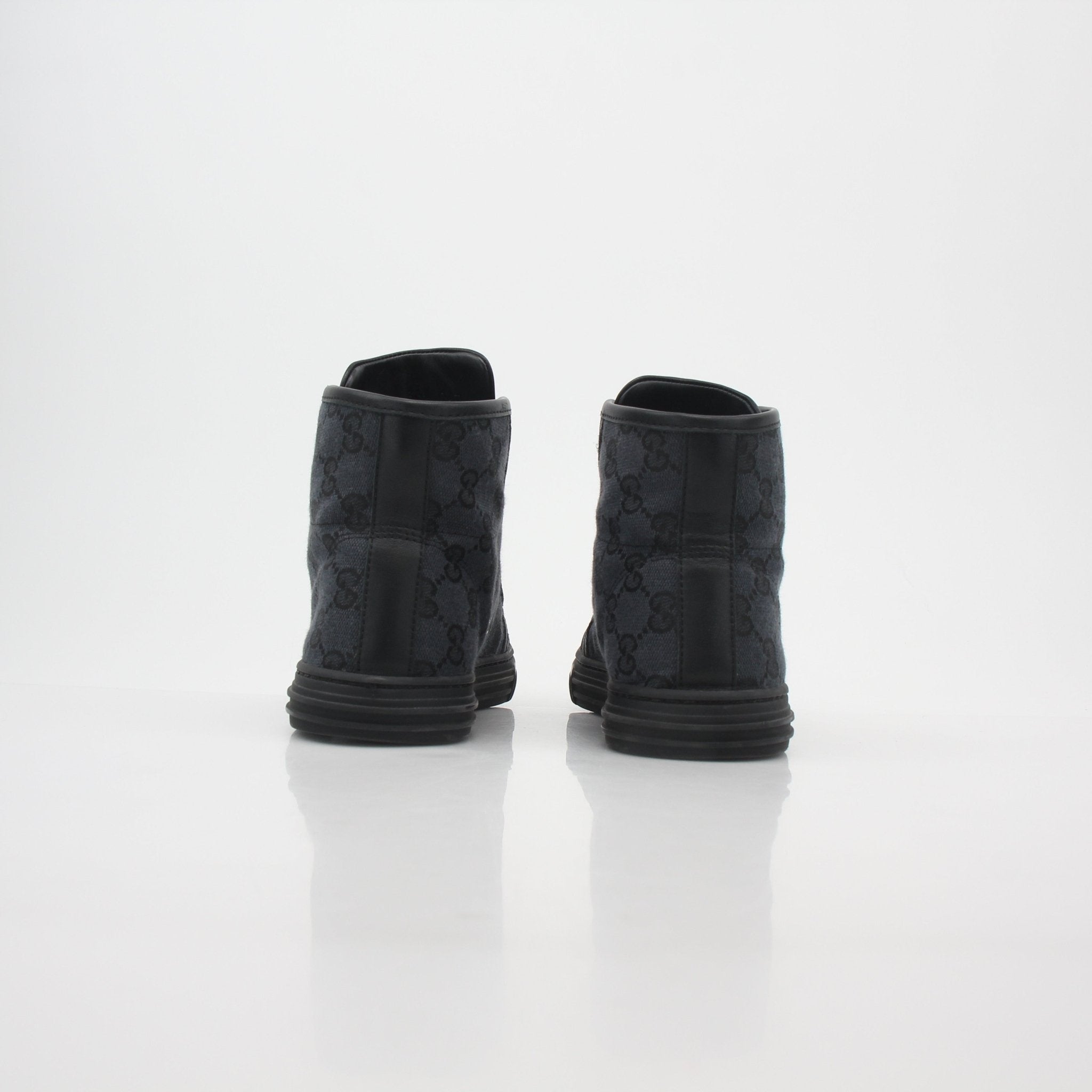 Gucci black GG canvas high-top sneakers with white rubber soles and laces, showcasing the luxury shoe design.