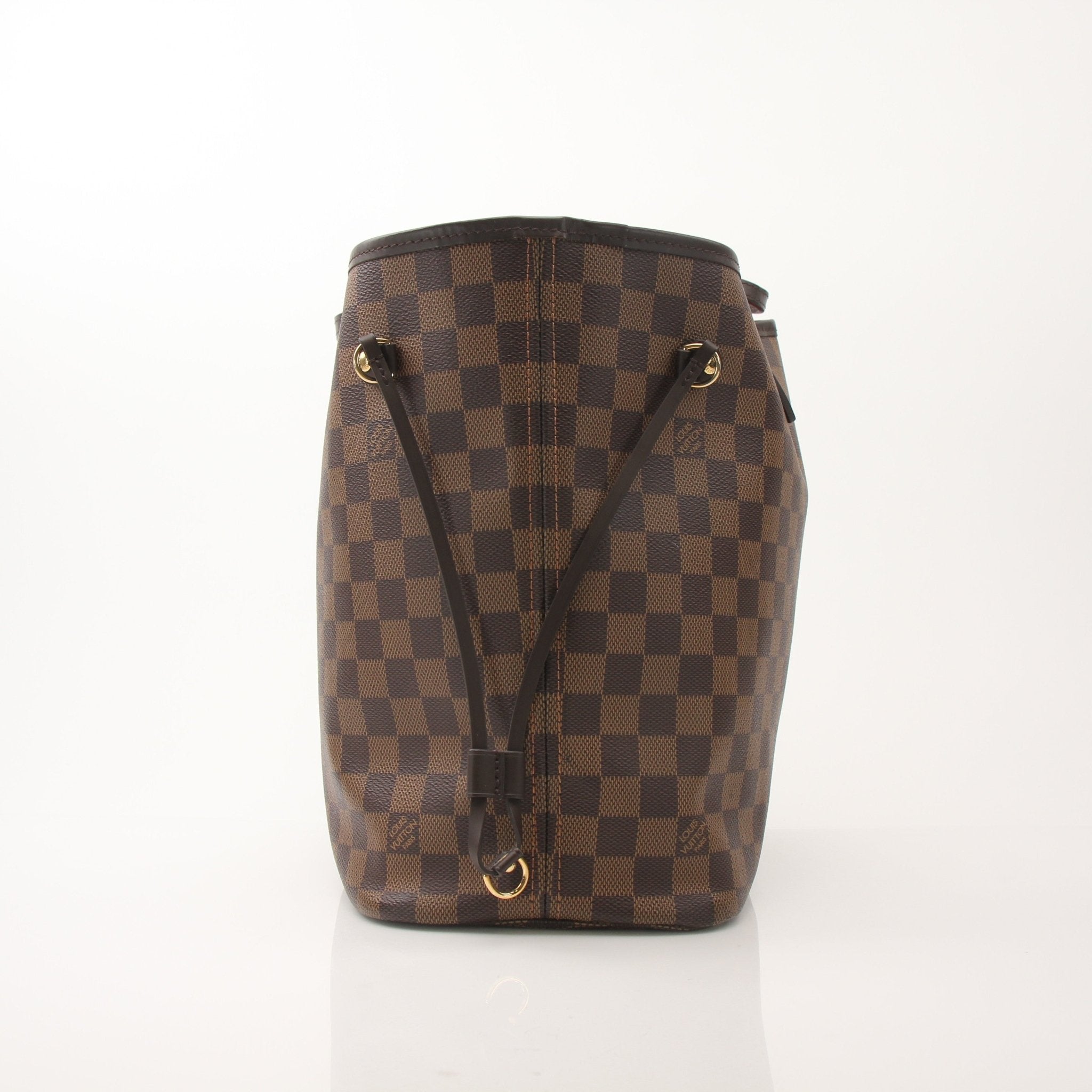 Louis Vuitton Neverfull MM tote bag in Damier Ebene canvas with leather handles, resting on a surface.