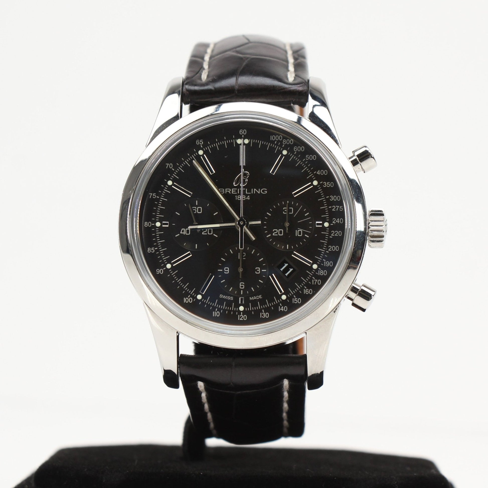 Gold & Beyond Breitling automatic chronograph watch with black dial, stainless steel case, and leather strap on a display stand.