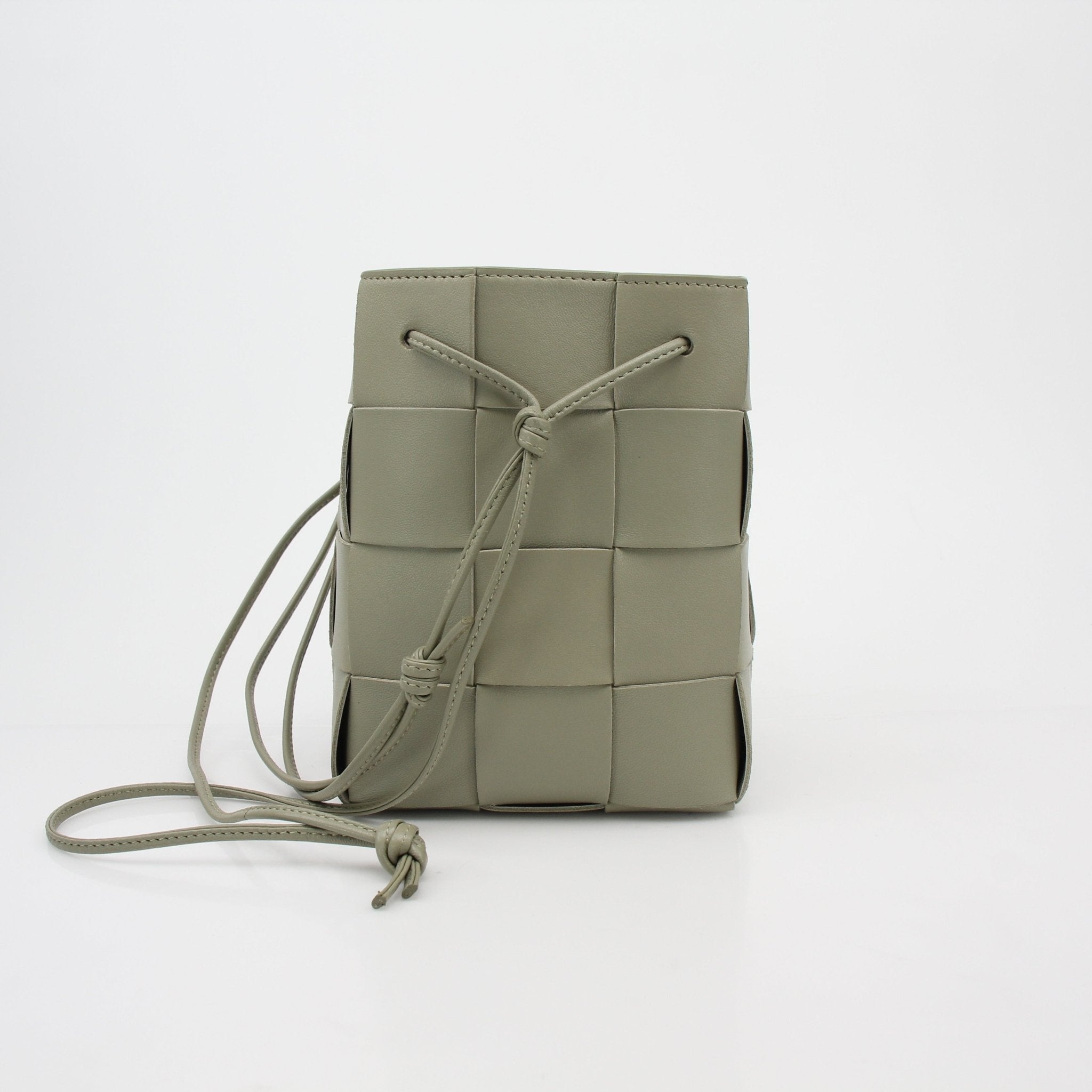 Gold & Beyond Bottega Veneta Chalk Cassette Bucket Bag handbag with a textured surface and drawstring closure.