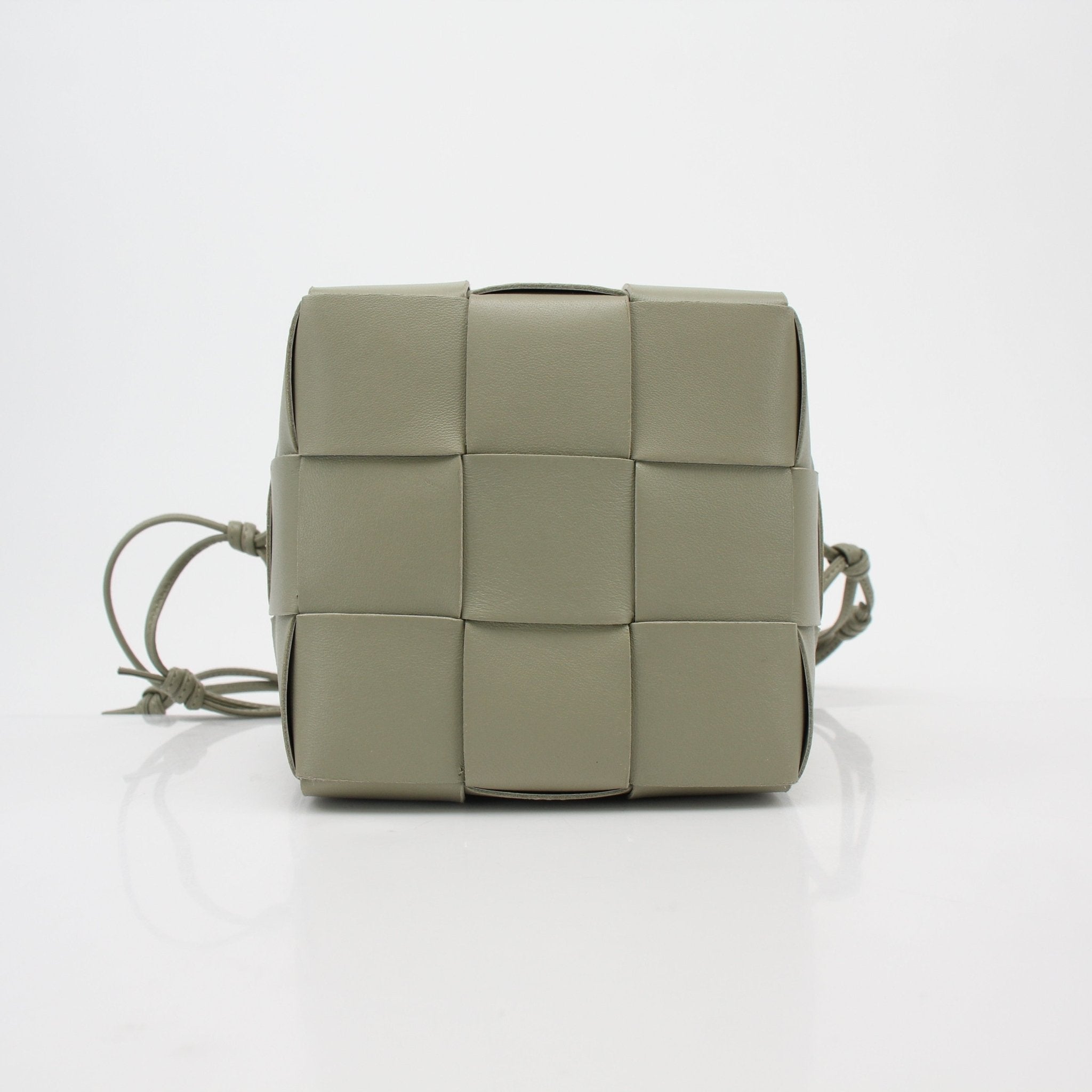 Bottega Veneta Chalk Cassette Bucket Handbag with gold-tone hardware and adjustable strap, displayed on a neutral background.