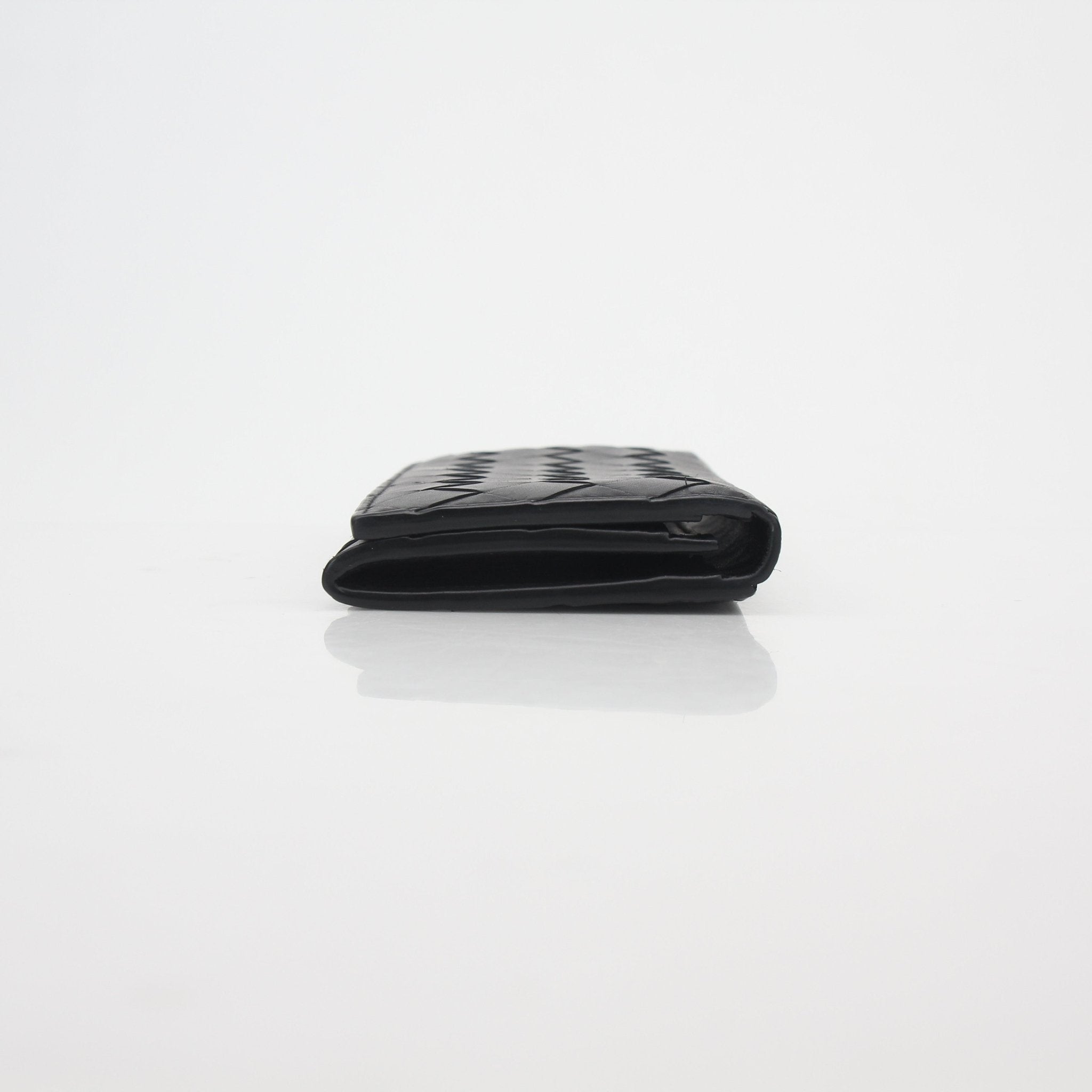 Black Bottega Veneta Intrecciato leather wallet with gold accents, showcasing the signature woven design, laid open to display card slots.