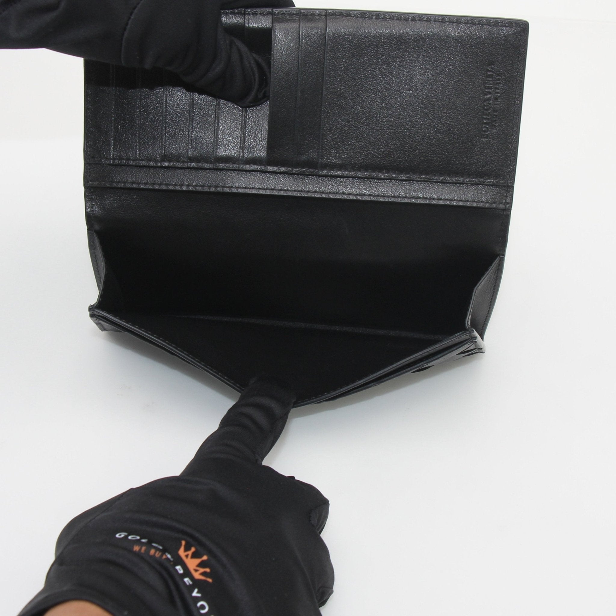 Black Bottega Veneta Intrecciato leather continental wallet with gold accents, showcasing detailed woven design and sleek interior.