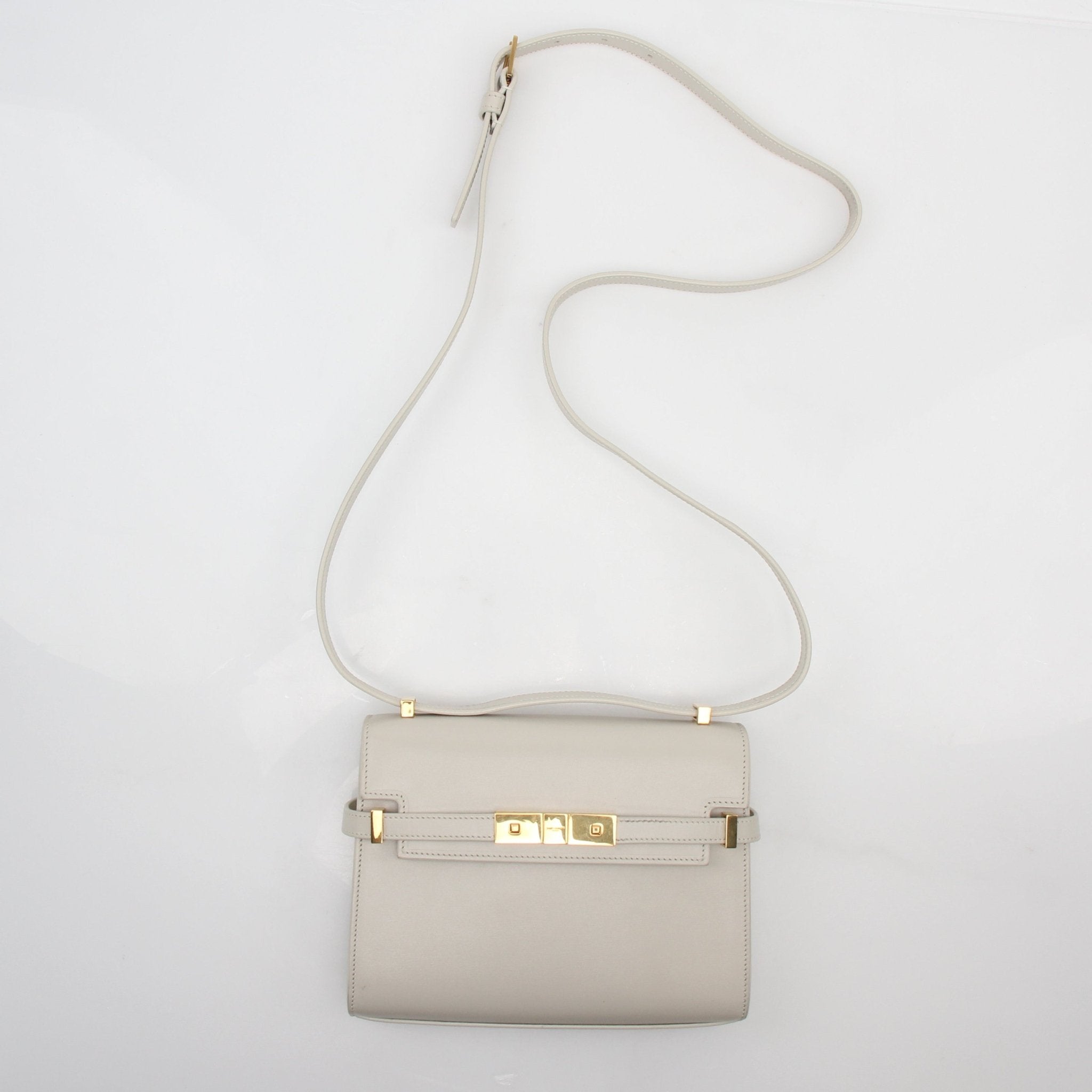 White Saint Laurent Manhattan shoulder bag with gold hardware, stylish handbag featuring a sleek design and shoulder strap.
