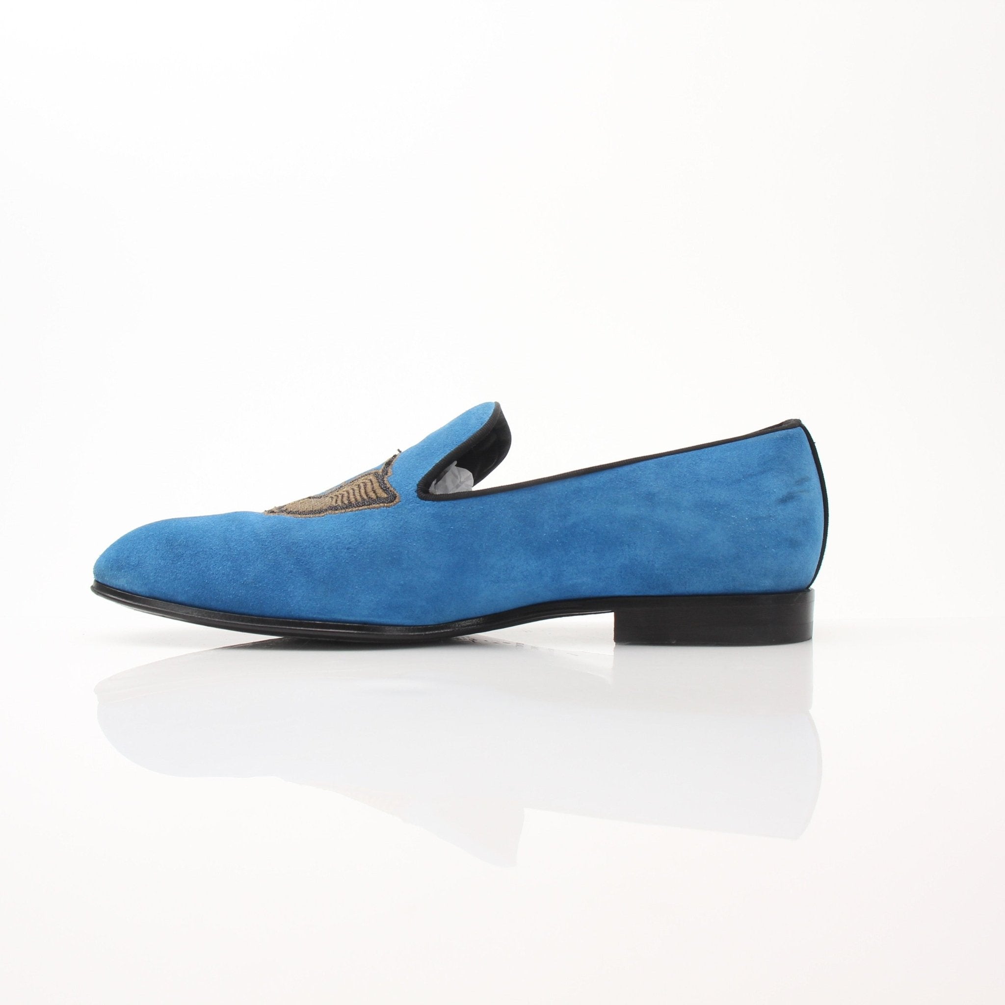Blue suede Louis Vuitton slip-on loafers with embroidered details, designed for stylish comfort.