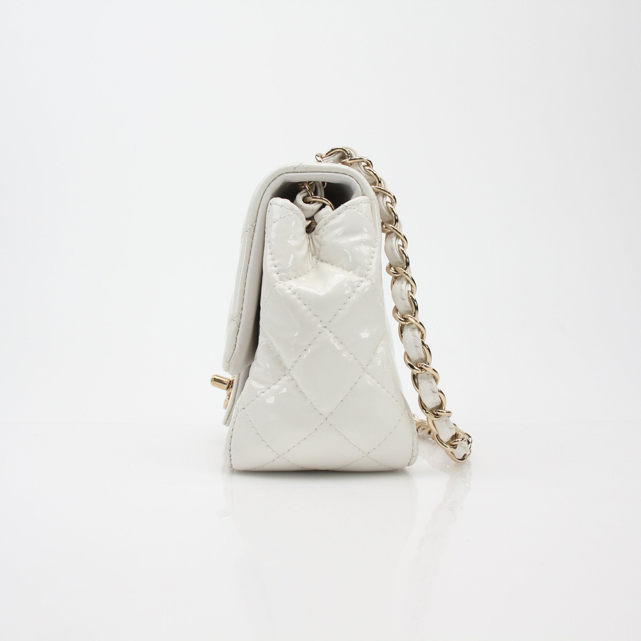 Gold & Beyond Chanel quilted patent leather mini flap handbag with gold chain strap and signature Chanel logo detail.