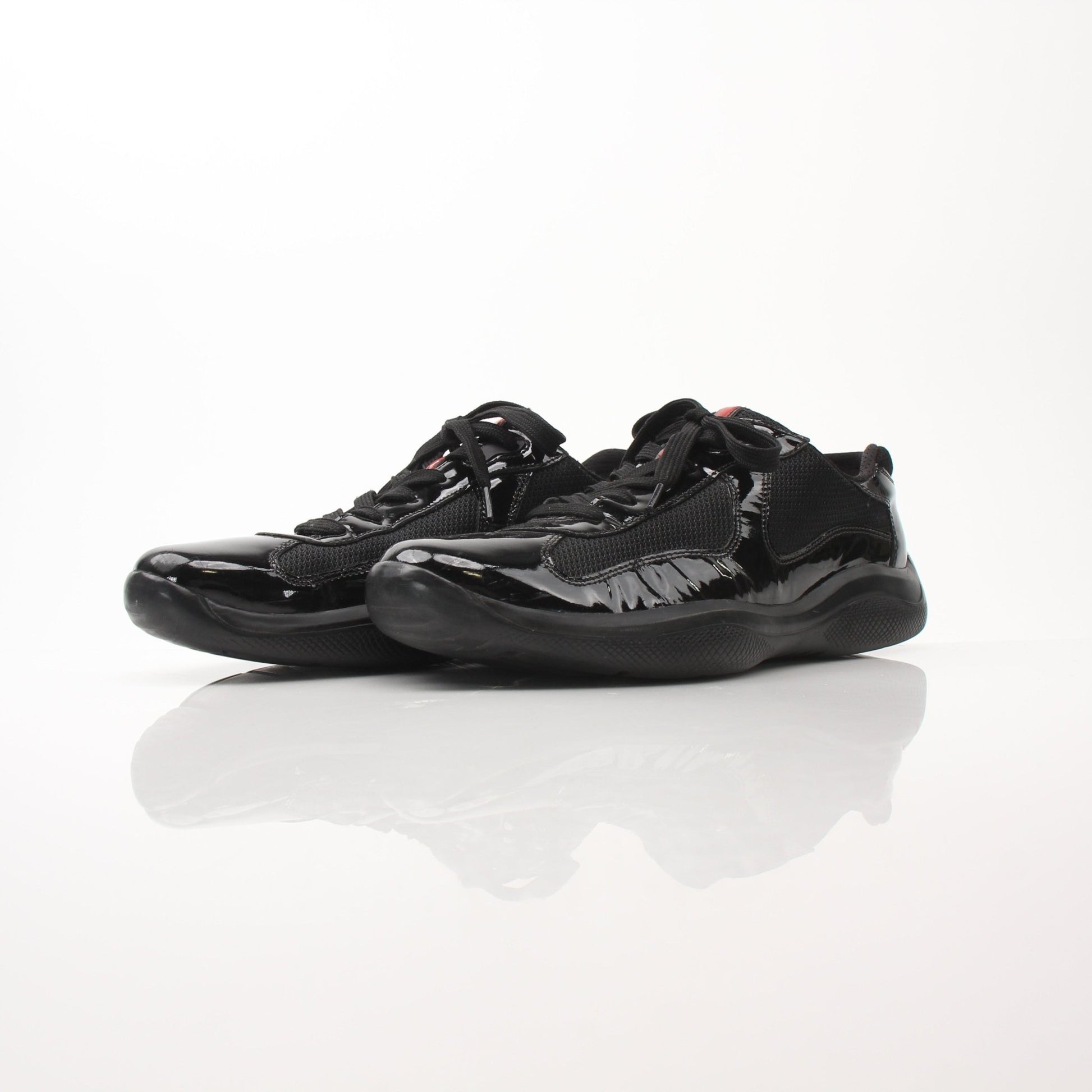 Prada Men’s America’s Cup black patent leather sneakers with sleek design, displayed on a plain background.