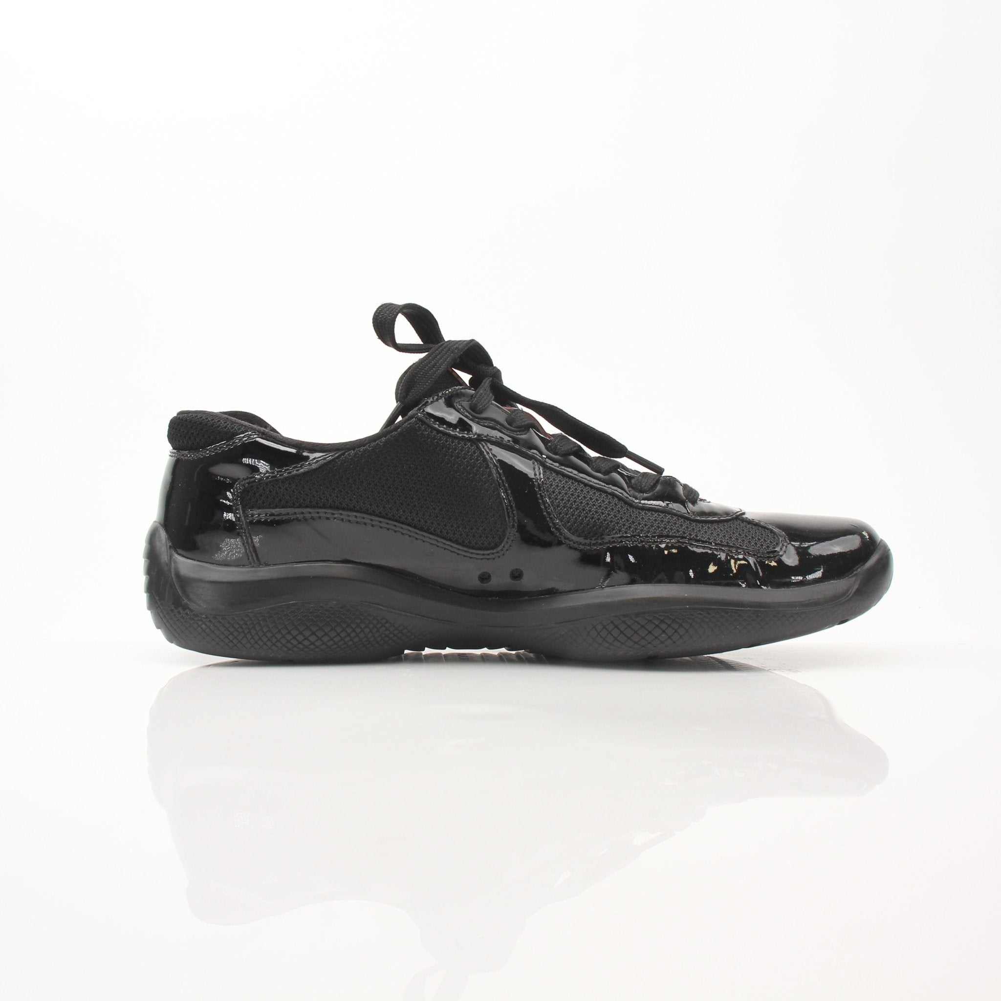 Prada Men’s America’s Cup black patent leather sneakers with sleek design and white sole, displayed on a plain background.