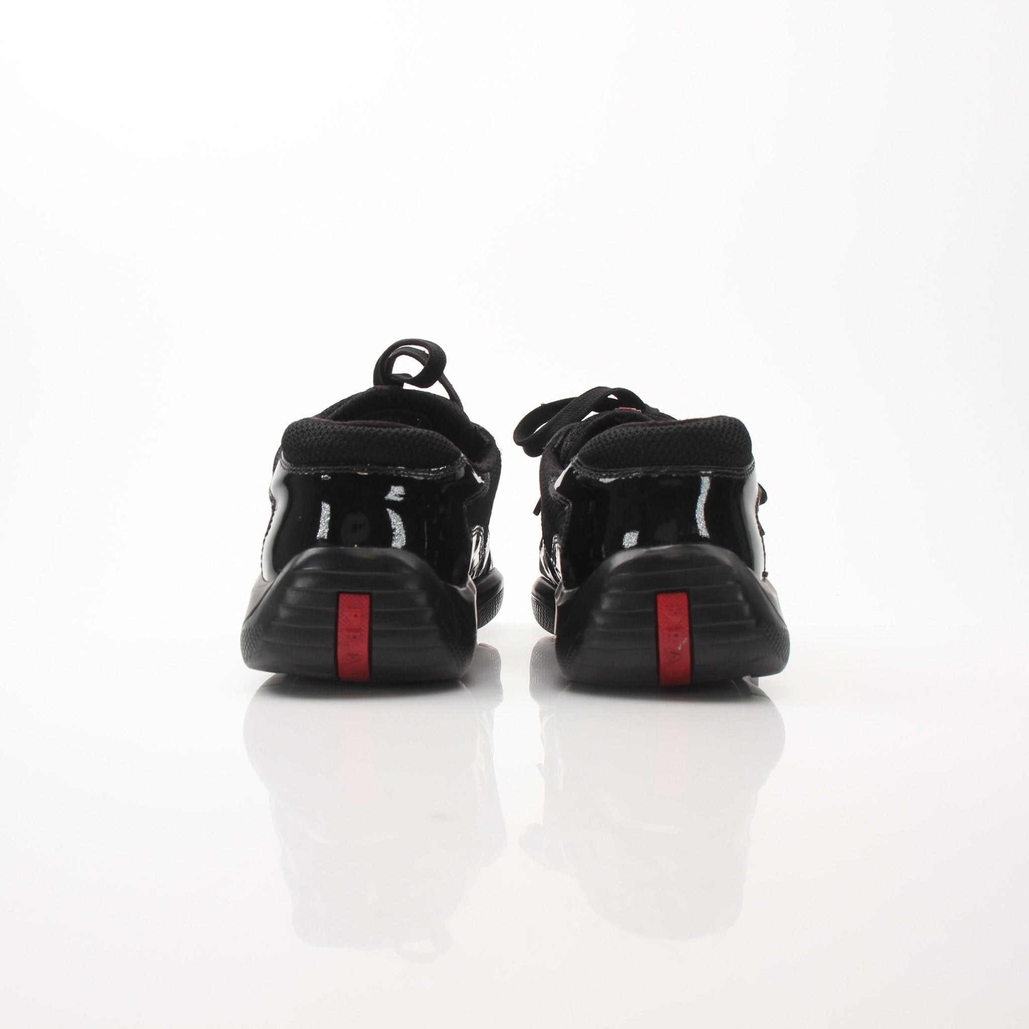 Gold & Beyond Prada Men’s America’s Cup black patent leather sneakers with sleek design and sporty laces.