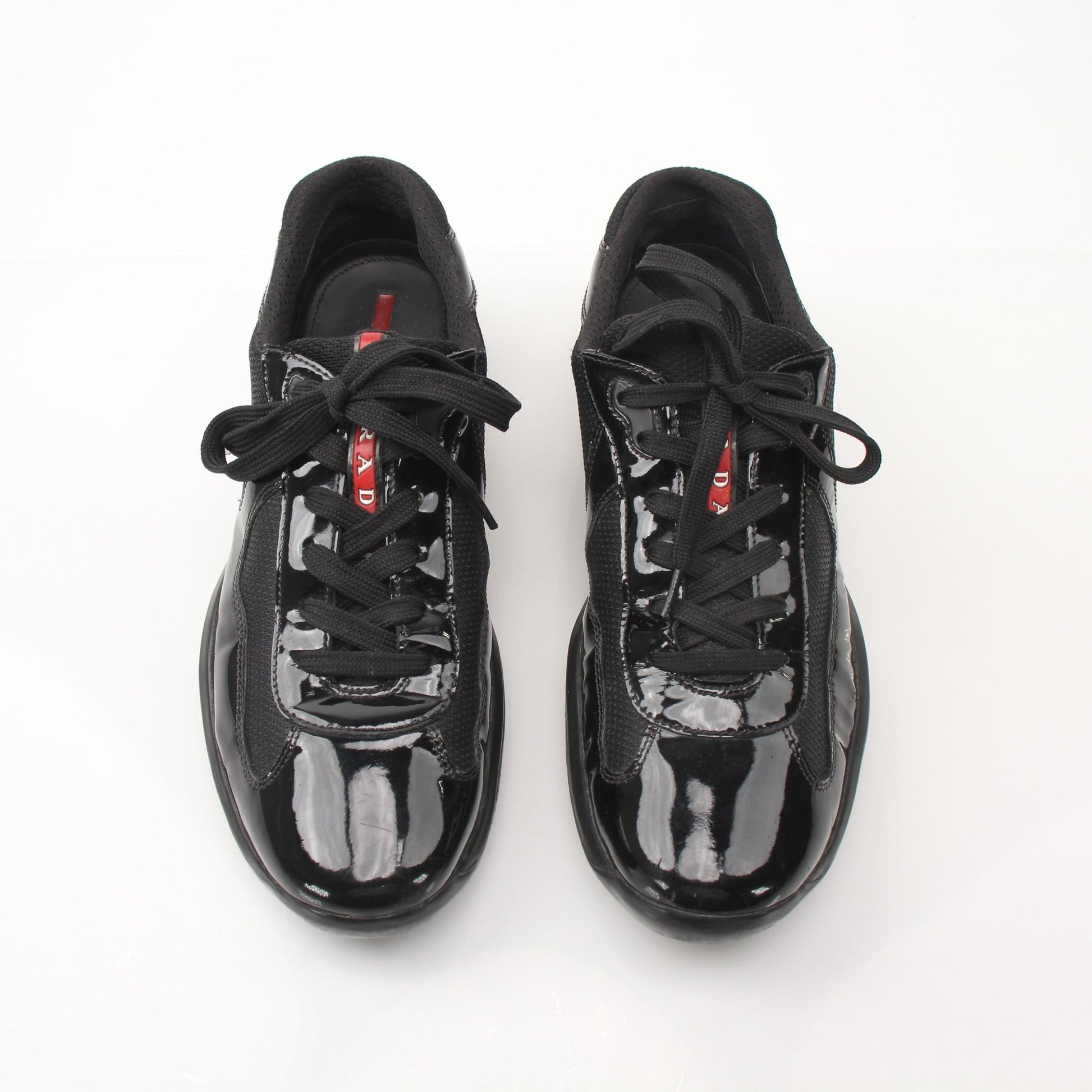 Black patent leather Prada men's America’s Cup sneakers with gold accents, showcasing sleek, stylish shoe design from Gold & Beyond.