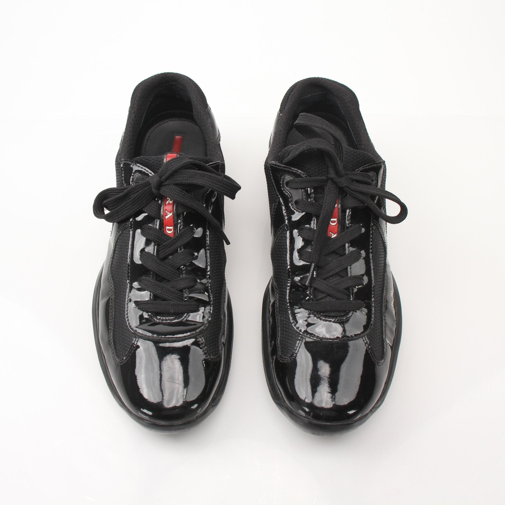 Black patent leather Prada men's America’s Cup sneakers with gold accents, showcasing sleek, stylish shoe design from Gold & Beyond.