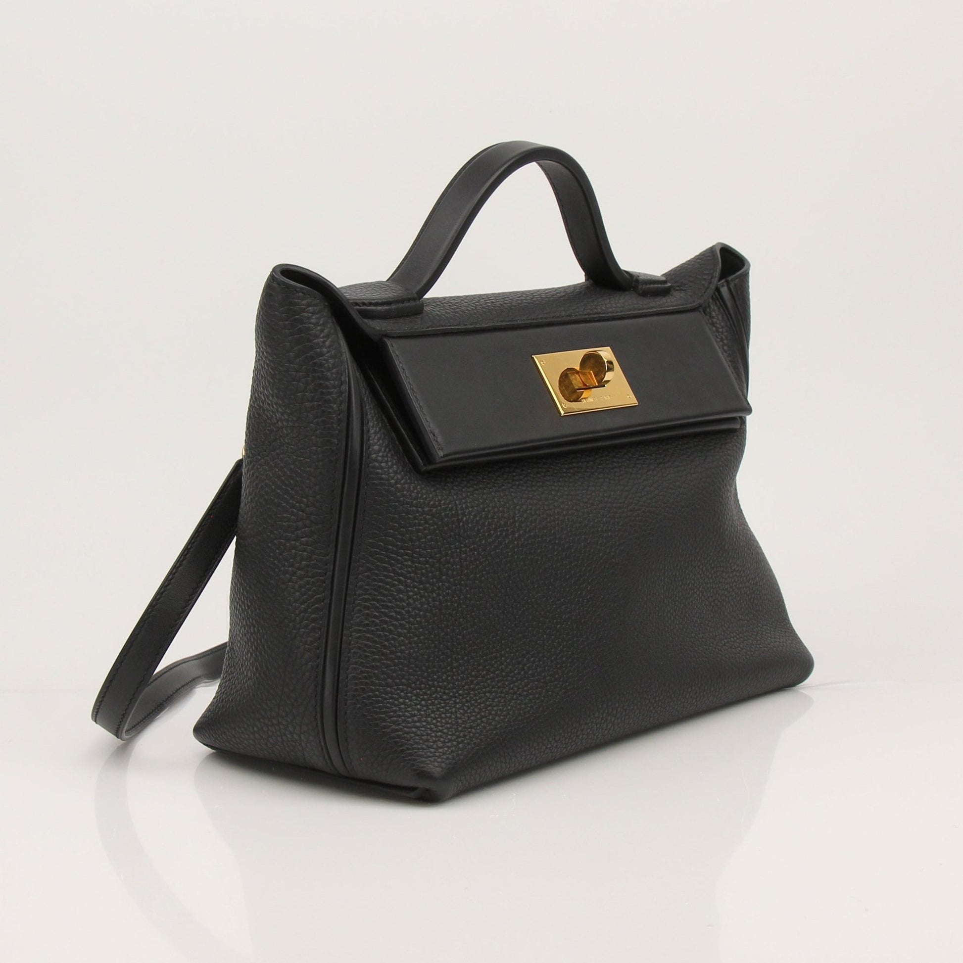 Hermès Top Handle Clemence handbag in beige leather with gold hardware, featuring a structured design and top handle.