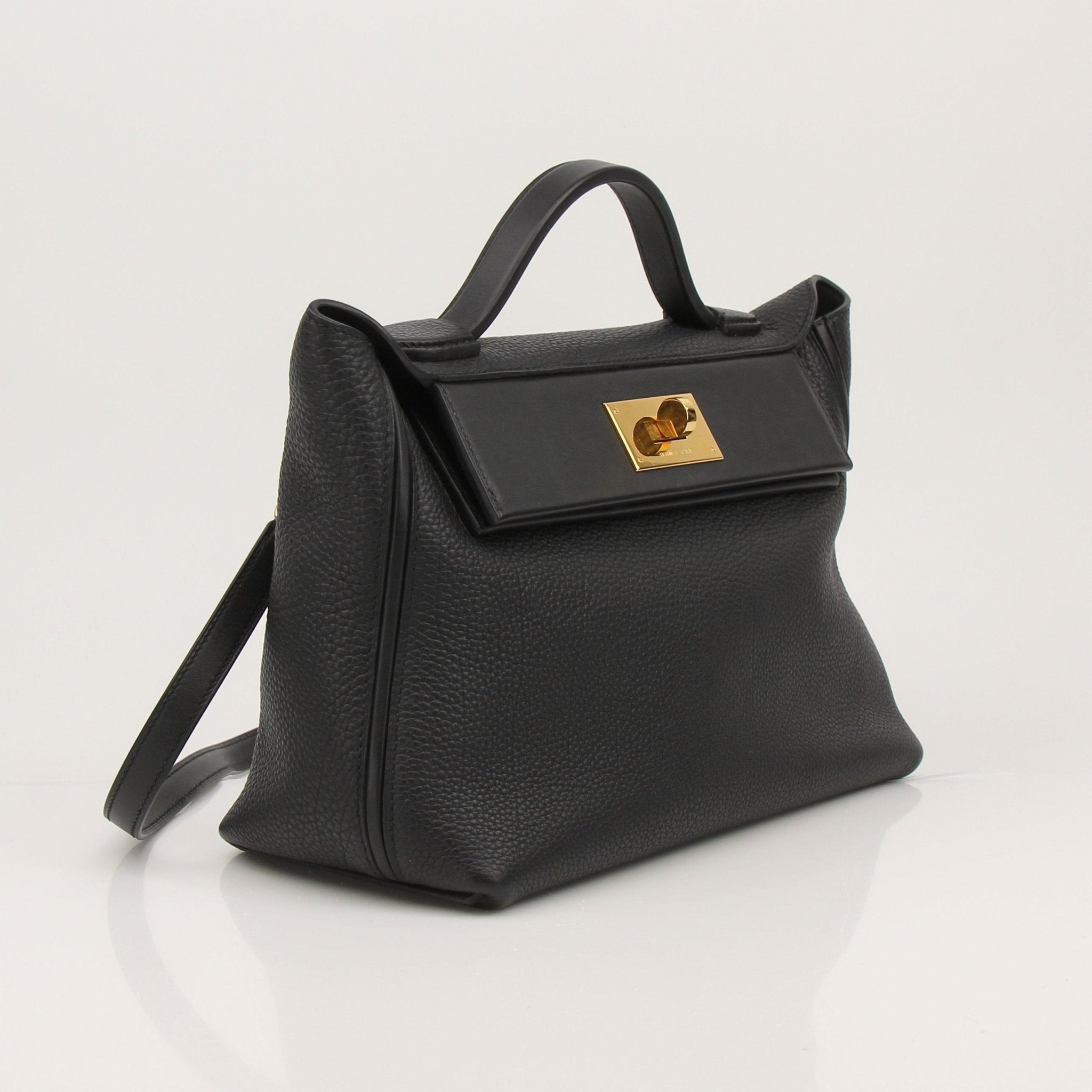 Hermès Top Handle Clemence handbag in beige leather with gold hardware, featuring a structured design and top handle.