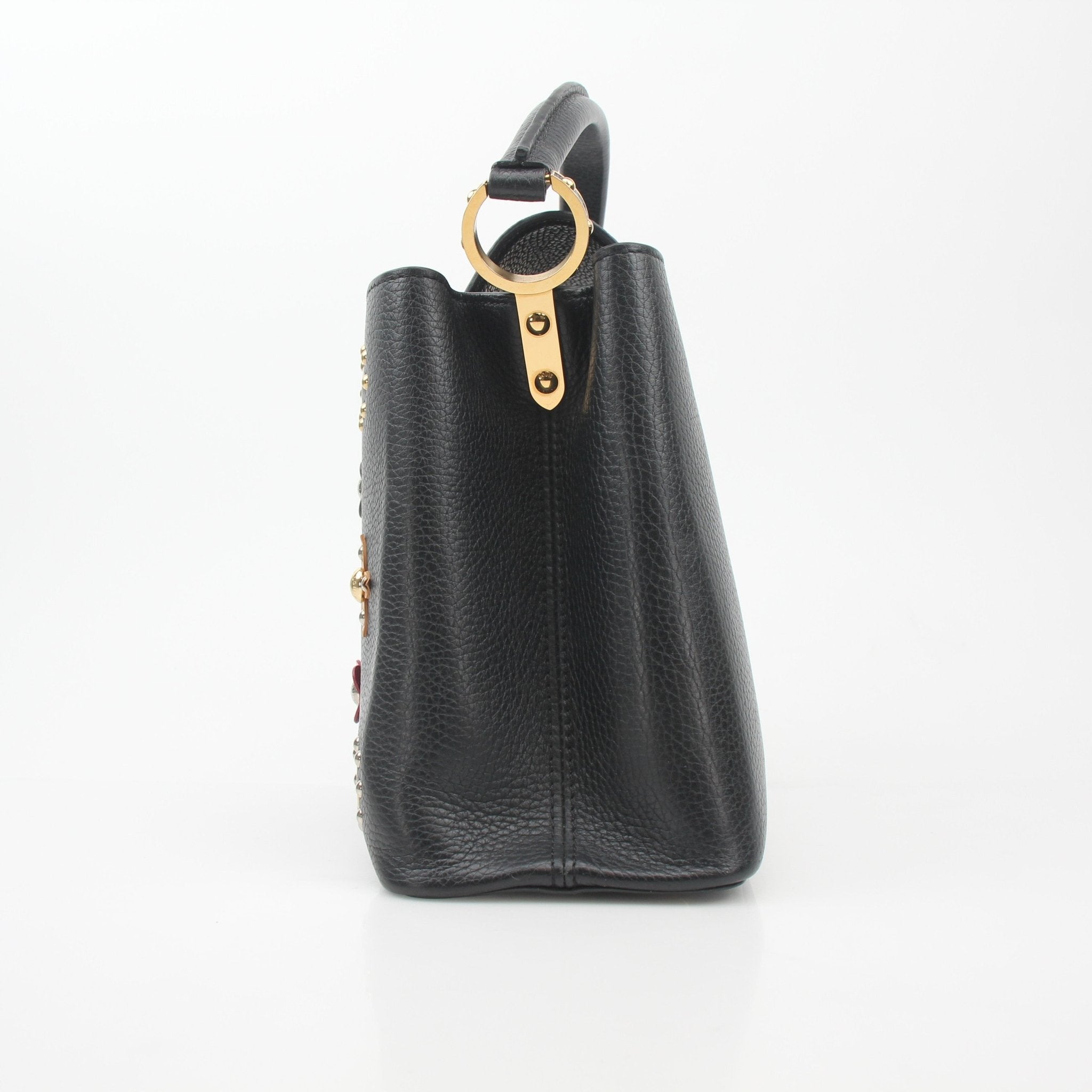 Louis Vuitton Capucines PM handbag with floral details, black leather and gold accents, showcasing elegant craftsmanship and design.