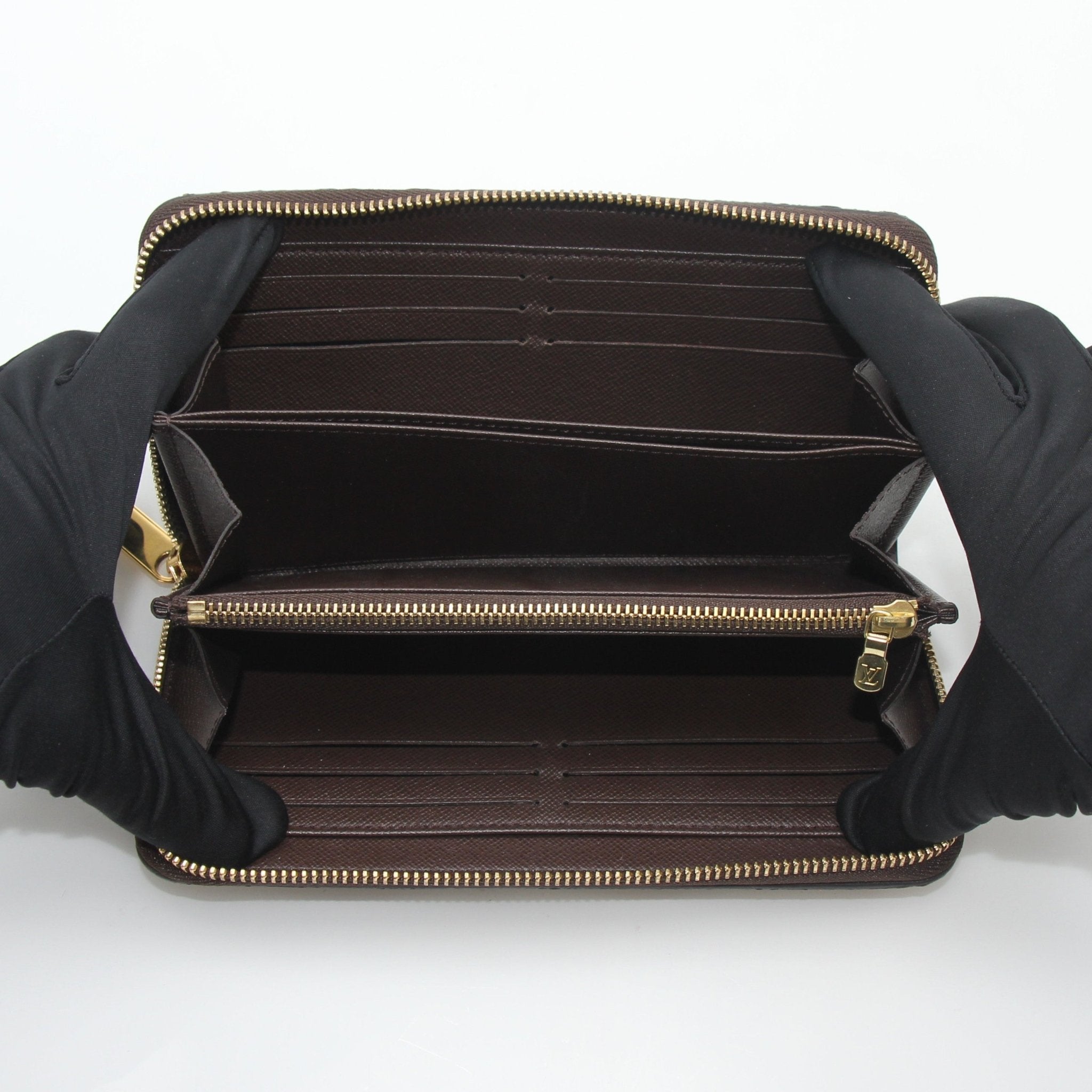 Louis Vuitton Damier Ebene Zippy Wallet with gold accents, featuring checkered pattern and multiple card slots.