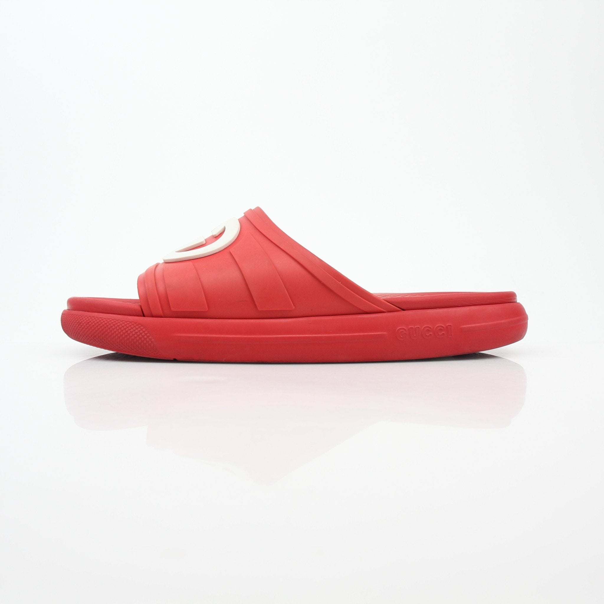 Gucci red interlocking G slide sandals with open toe and slip-on design, displayed on a neutral background.