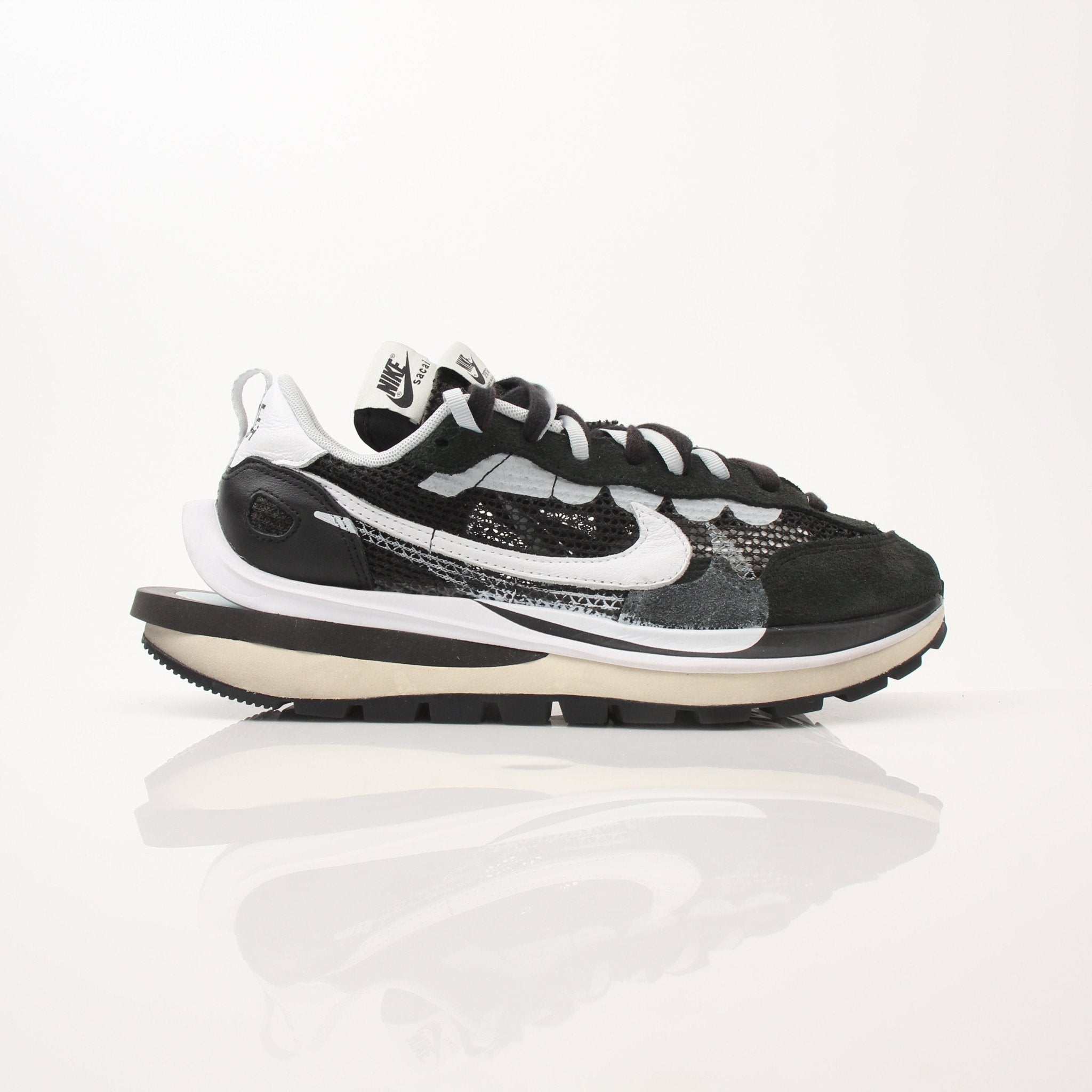 Nike x Sacai VaporWaffle men's sneakers in gray and white with layered design and Nike branding, displayed on a neutral background.