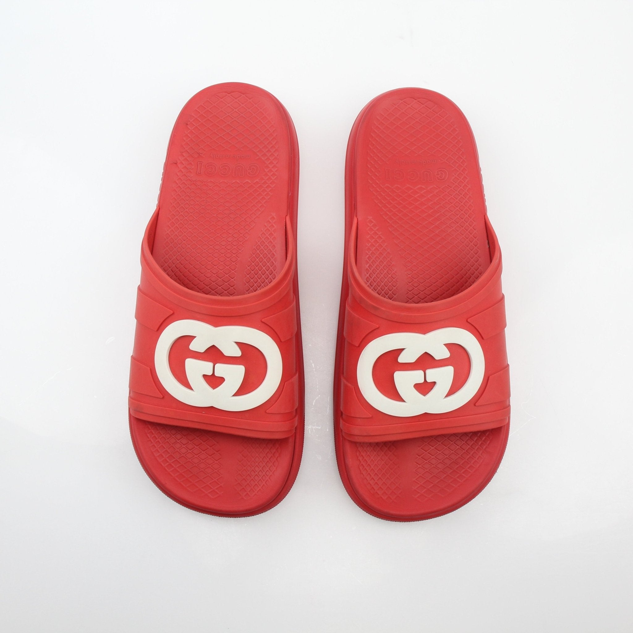 Gucci red interlocking G slide sandals with open toe design and flat sole, displayed on a neutral background