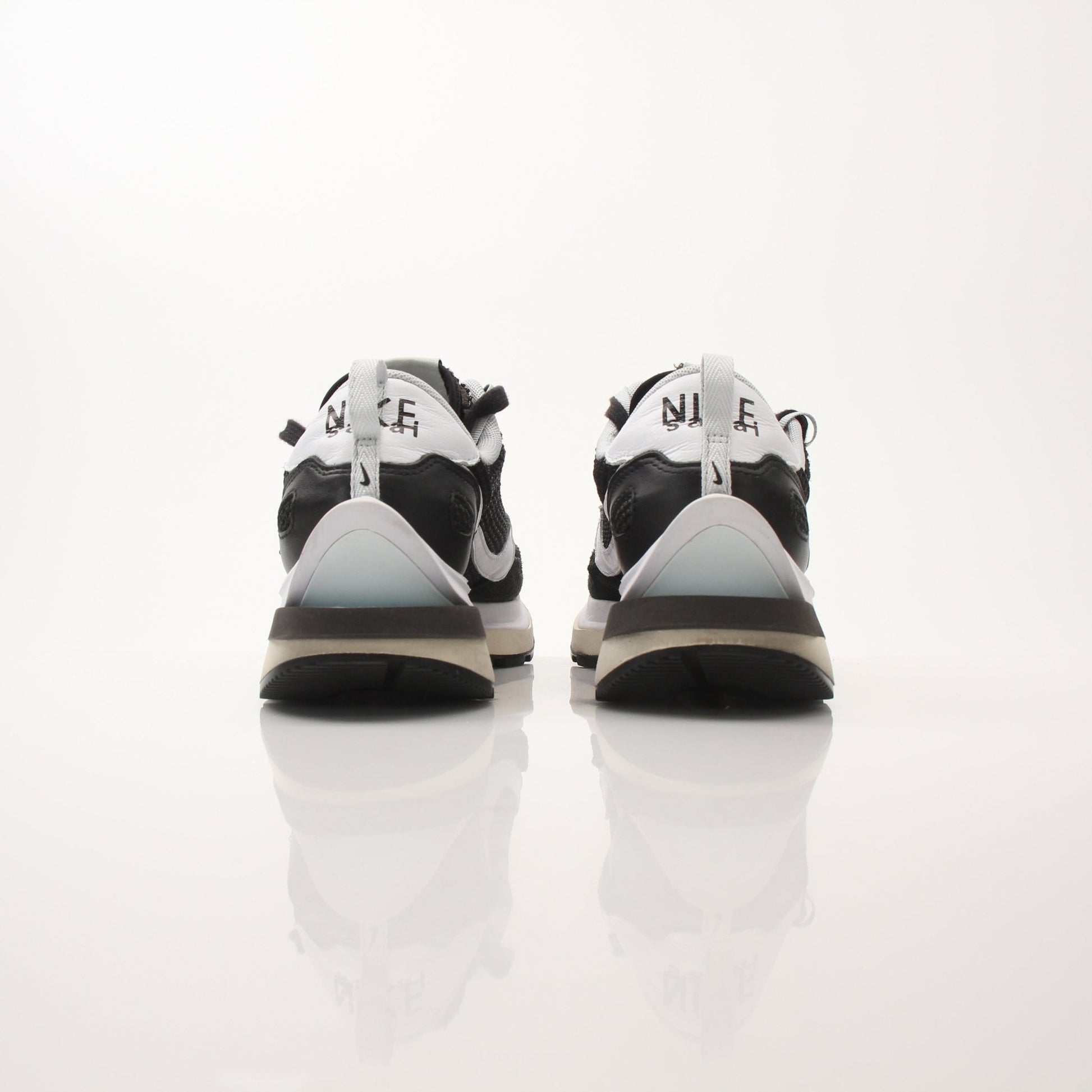 Nike x Sacai men's VaporWaffle sneakers, black and white shoes with layered design and Nike branding, on a white background.