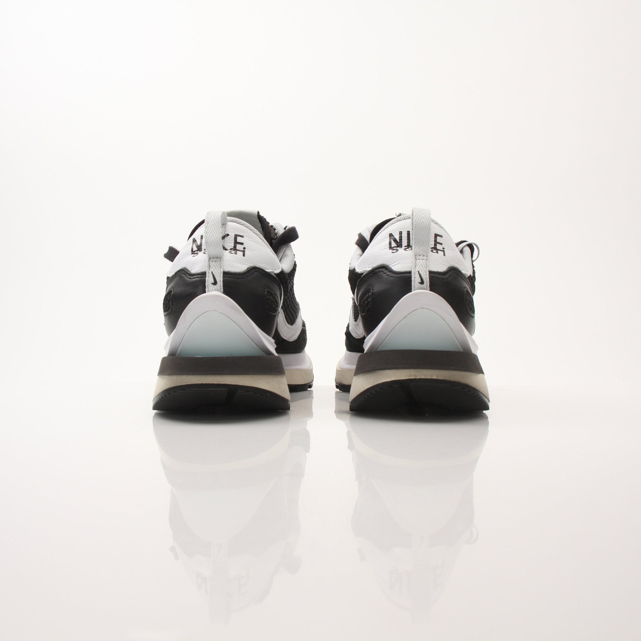 Nike x Sacai men's VaporWaffle sneakers, black and white shoes with layered design and Nike branding, on a white background.