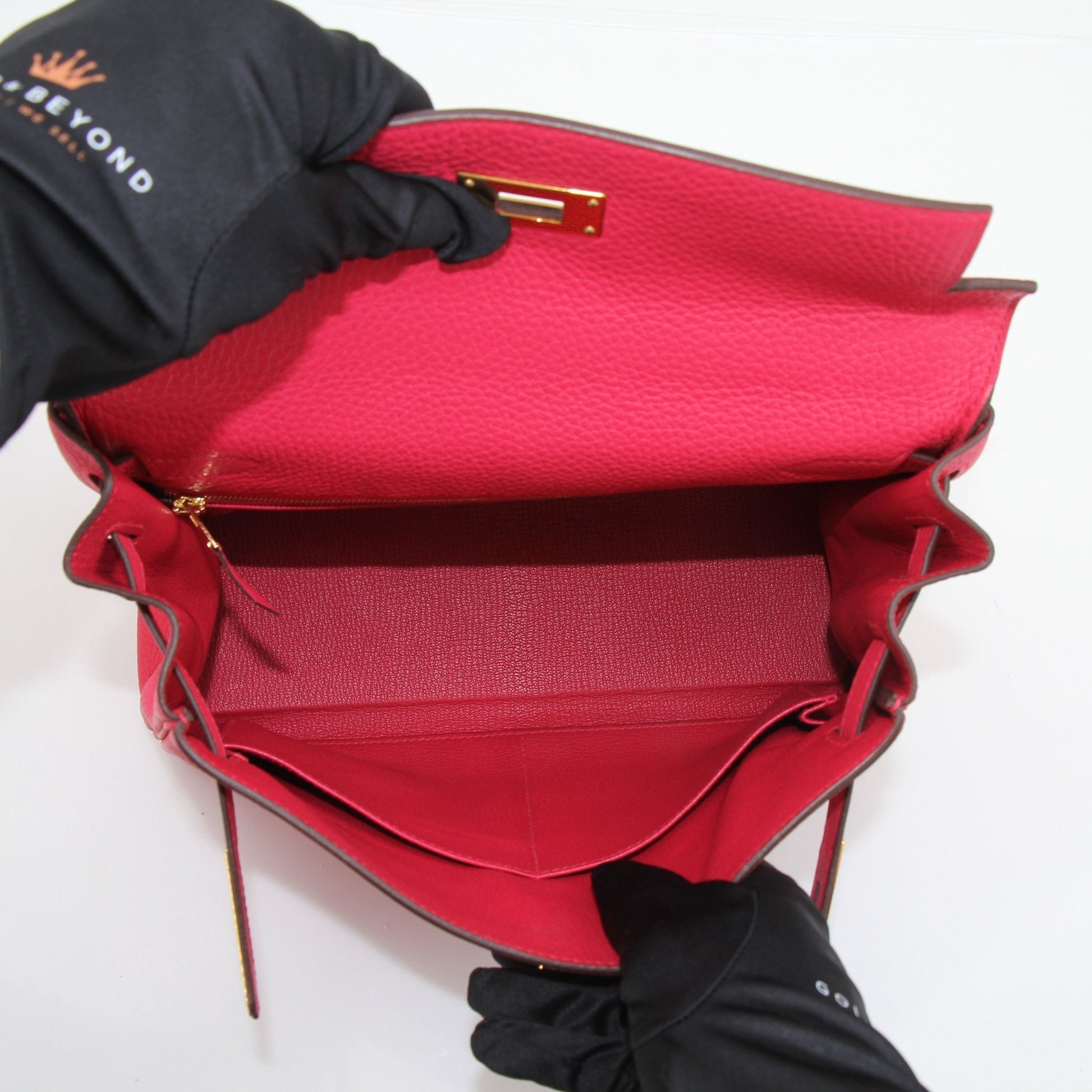 Hermès Kelly 28 Pink Togo handbag with gold hardware, featuring a structured design and top handle, displayed on a neutral background.