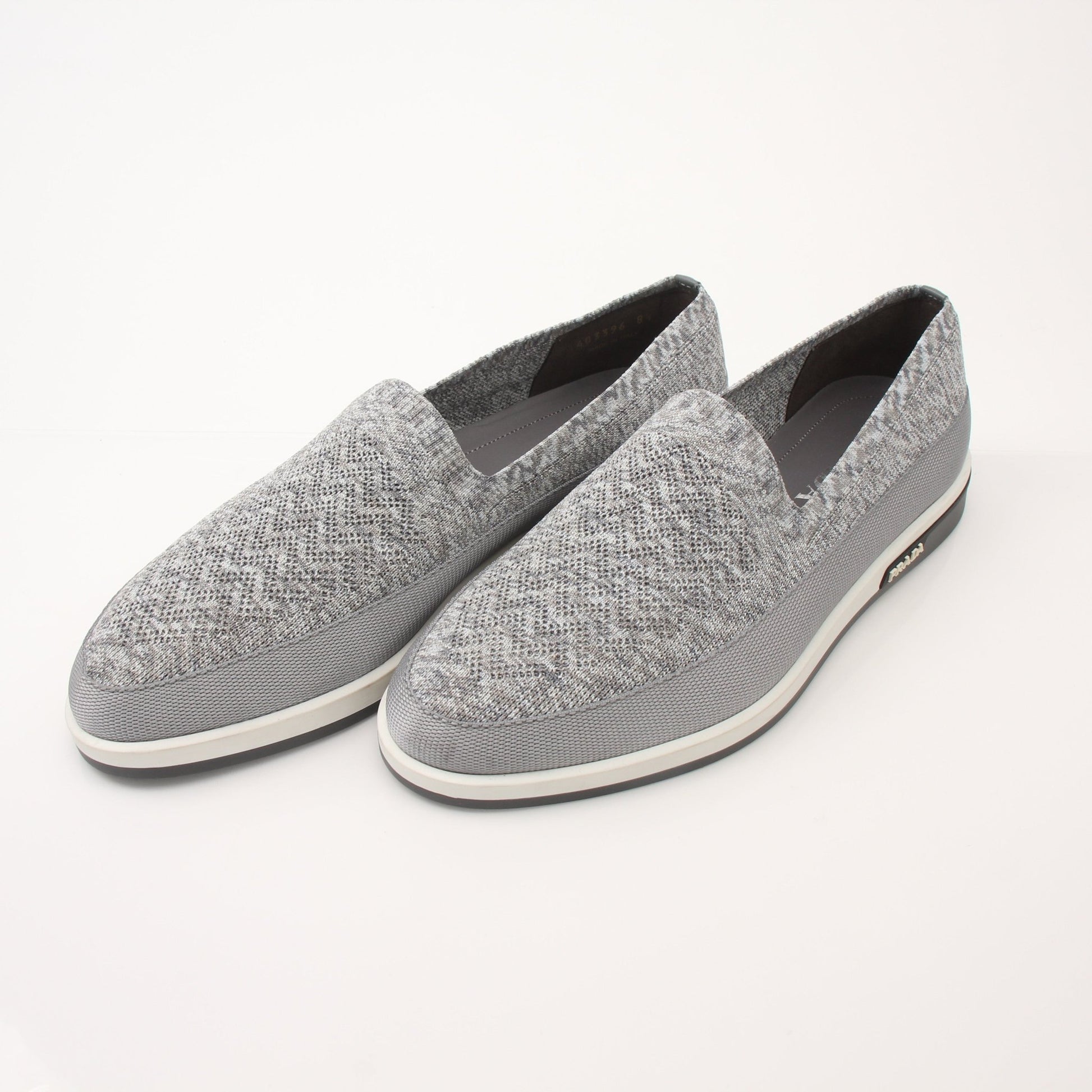 Prada Men’s Saint Tropez slip-on sneakers in black leather with white soles, displayed on a plain background.