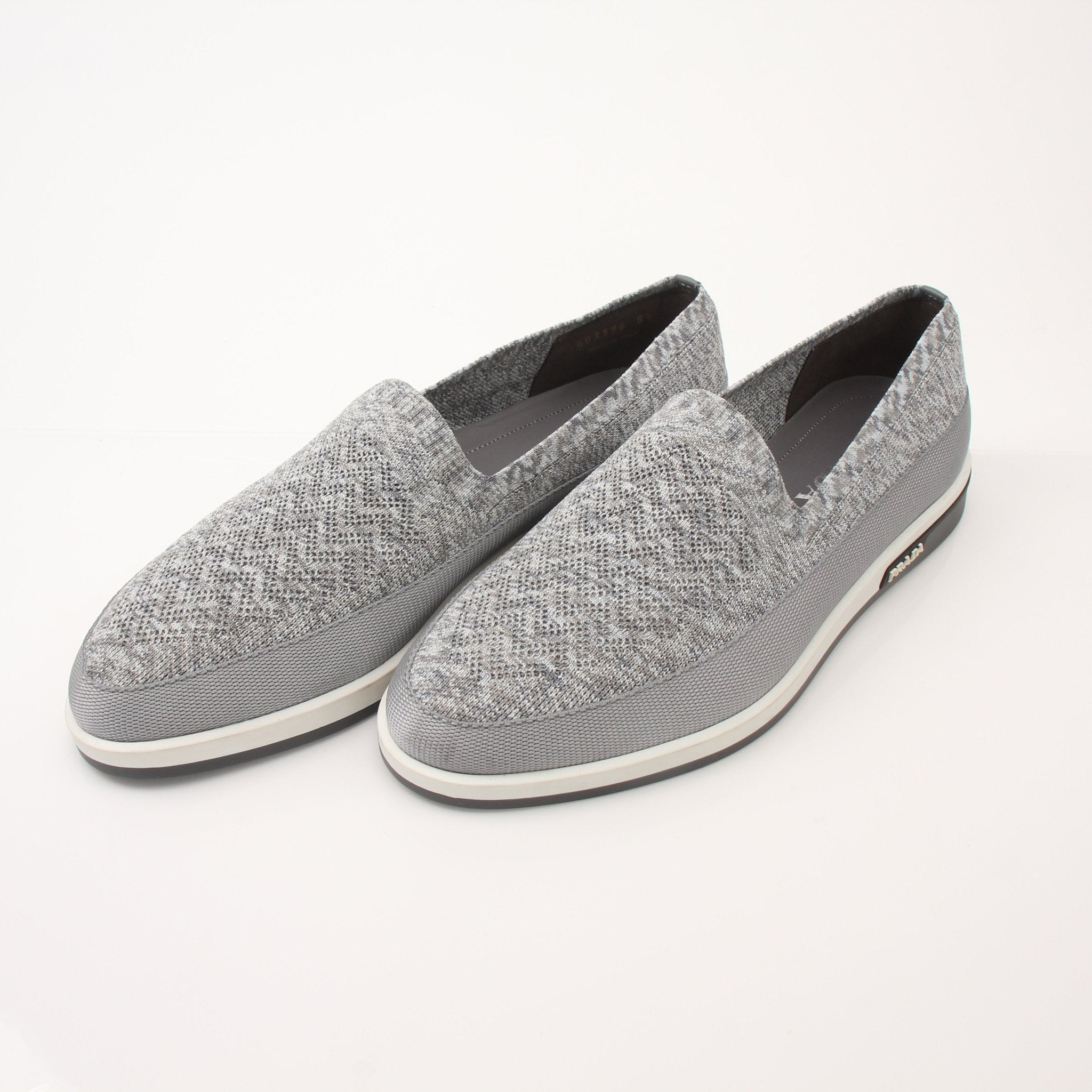 Prada Men’s Saint Tropez slip-on sneakers in black leather with white soles, displayed on a plain background.