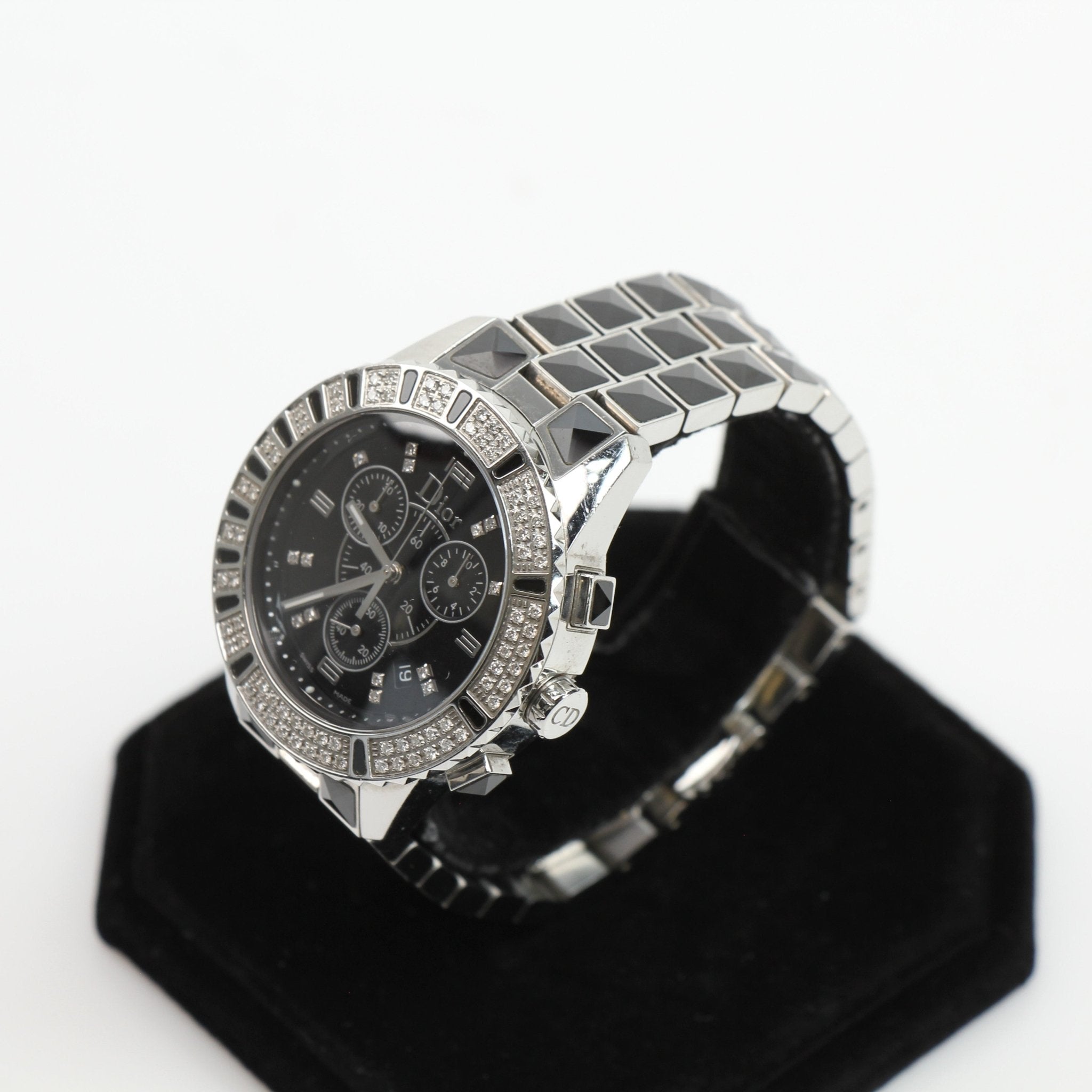 Dior Diamond Chronograph Watch with gold accents and a sleek dial, displayed on a stand against a neutral background.