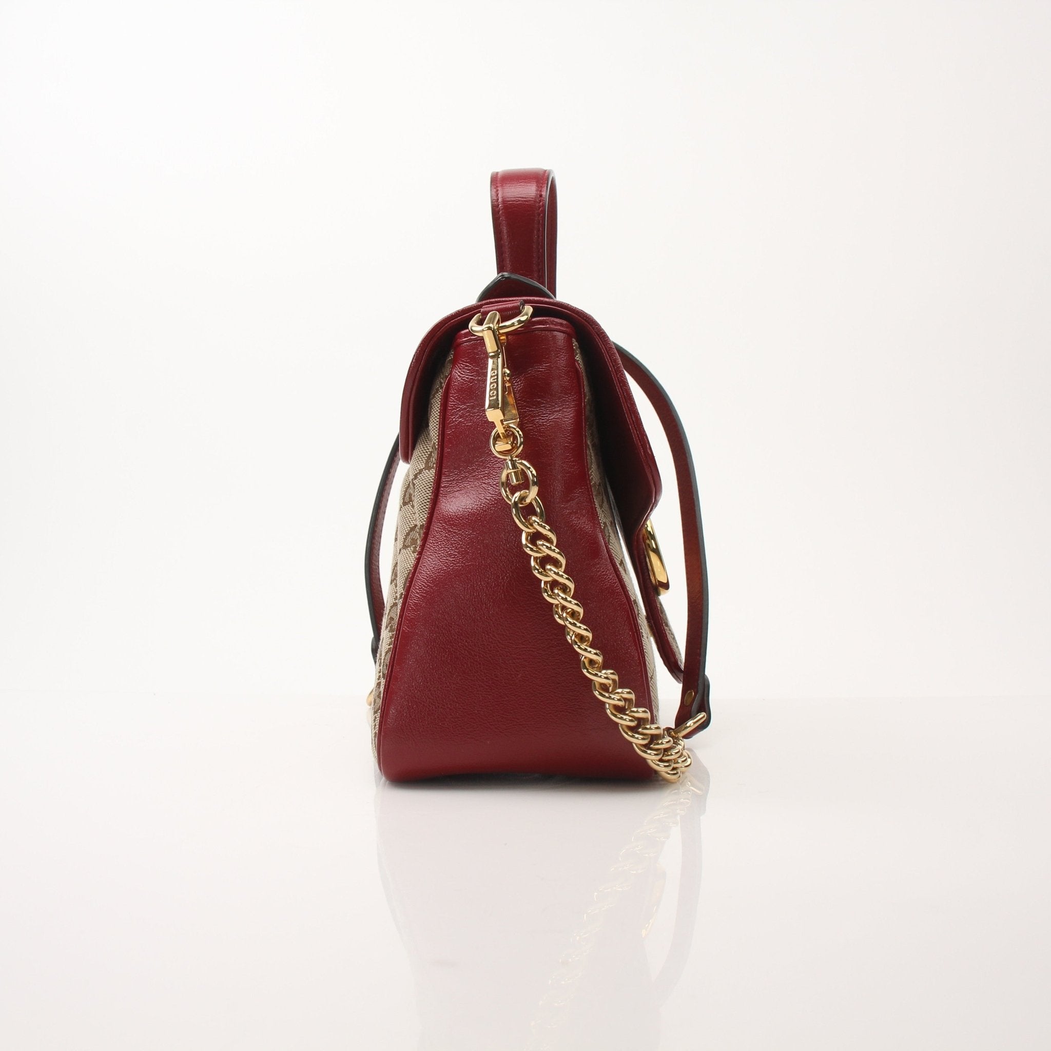 Gold & Beyond Gucci GG Marmont top handle handbag with quilted leather and gold hardware, displayed on a neutral background.