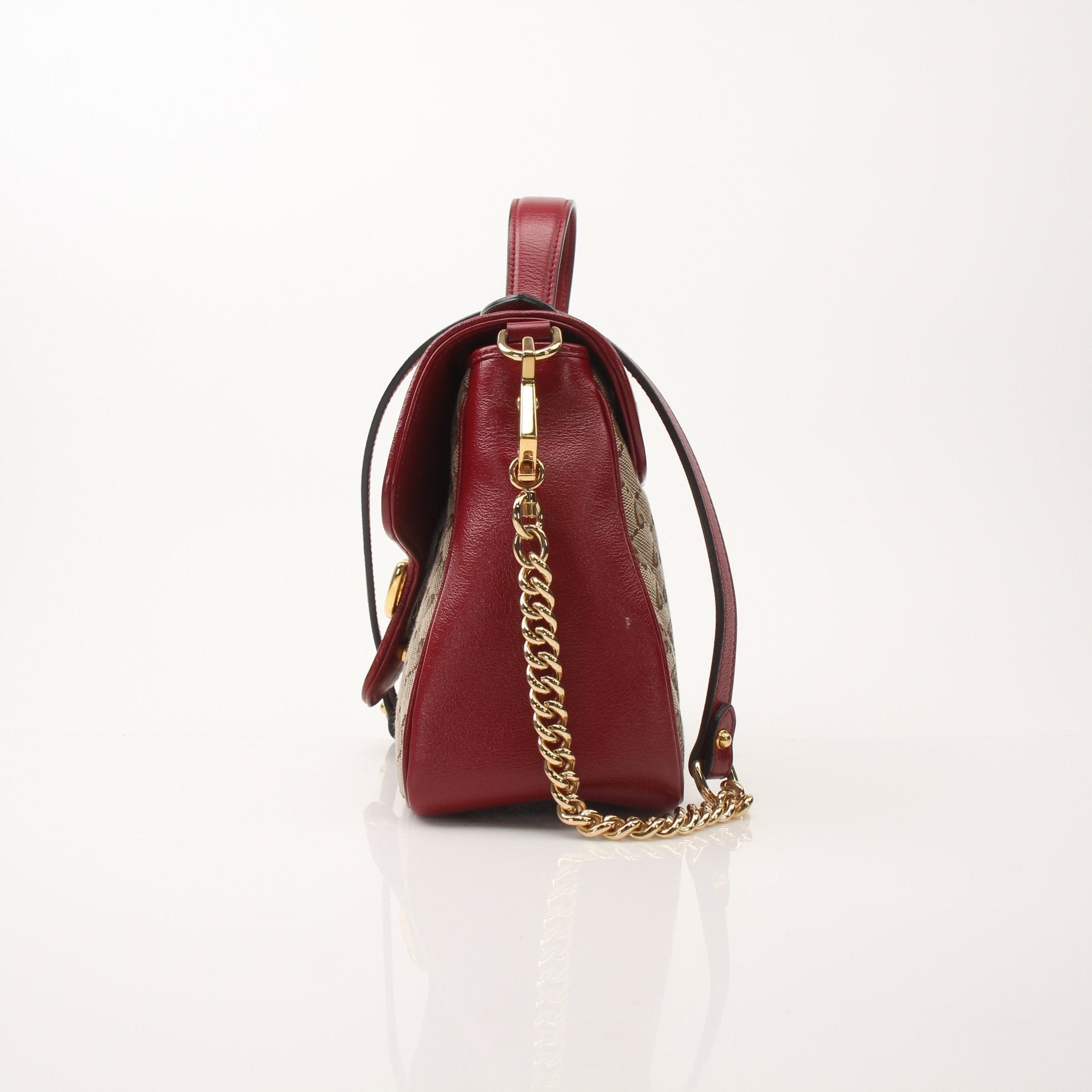 Gucci GG Marmont top handle handbag with gold chain strap and quilted leather in black, displayed on a white background.
