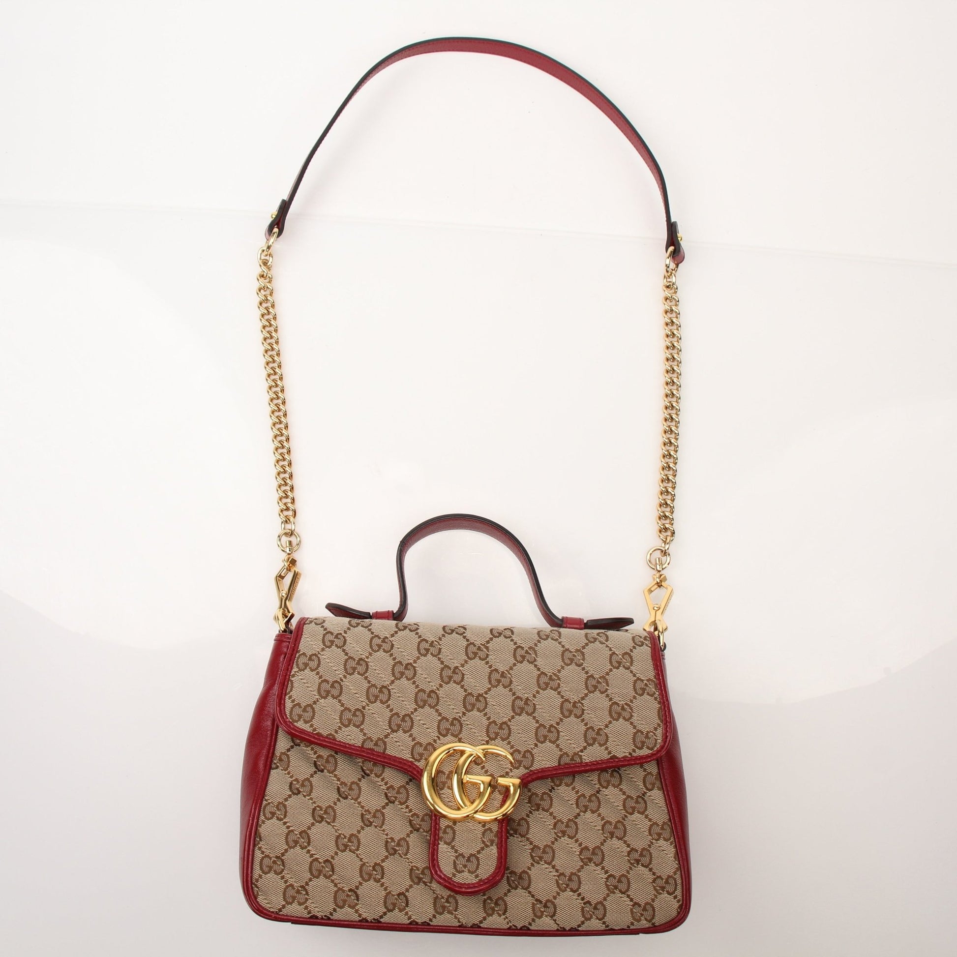 Gucci GG Marmont top handle handbag with quilted leather and gold-tone hardware, displayed on a neutral background.