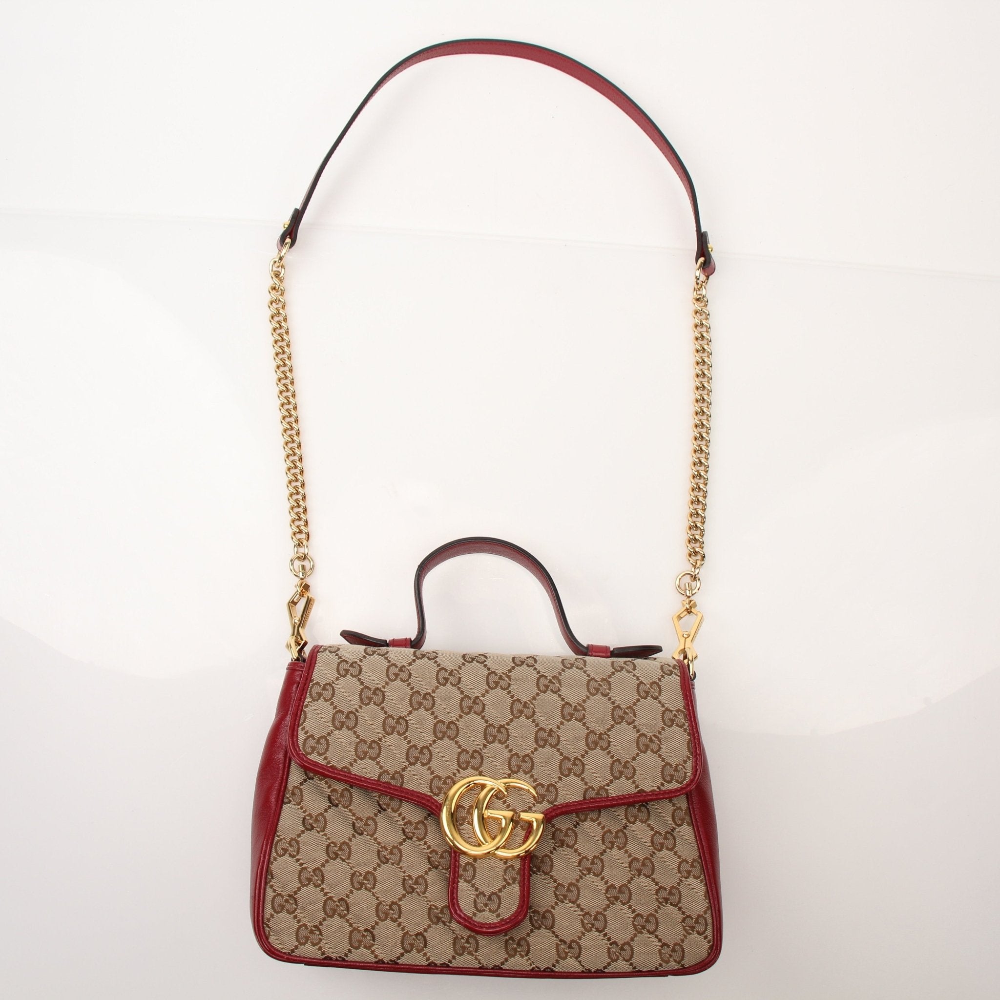 Gucci GG Marmont top handle handbag with quilted leather and gold-tone hardware, displayed on a neutral background.