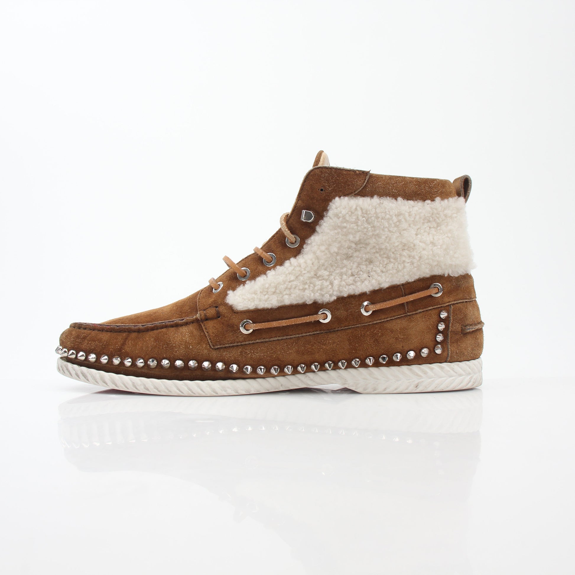 Christian Louboutin shearling flat boots with ankle-high design and luxurious shearling lining, shown in a stylish footwear image.