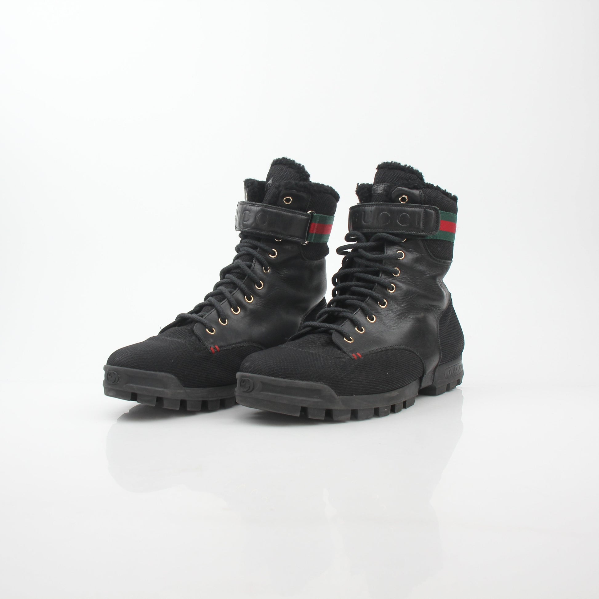 Gucci black Web accent combat boots with rugged sole and lace-up design, featuring signature branding and stylish detailing.