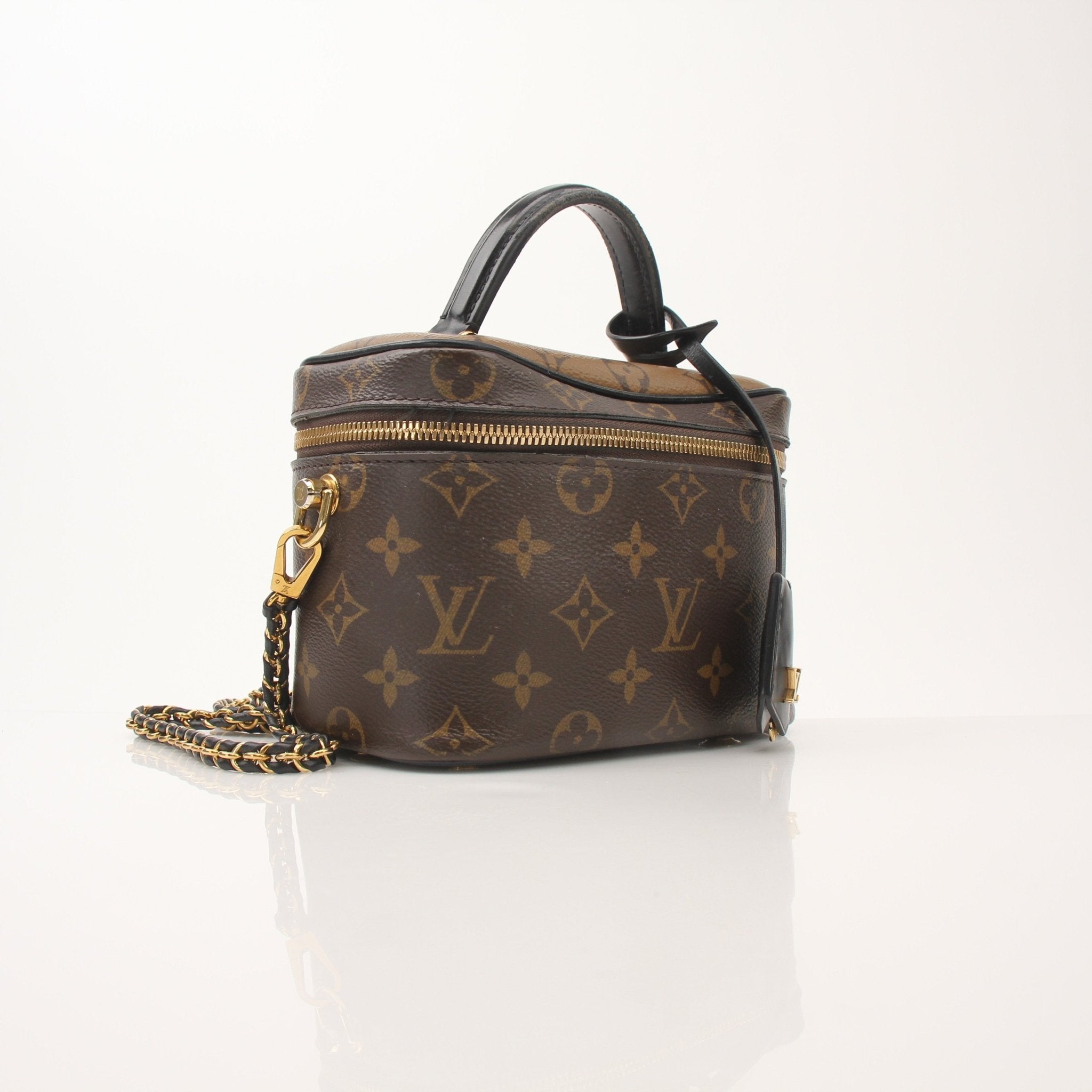Louis Vuitton Vanity PM top handle crossbody handbag in textured leather with gold accents and a structured design.