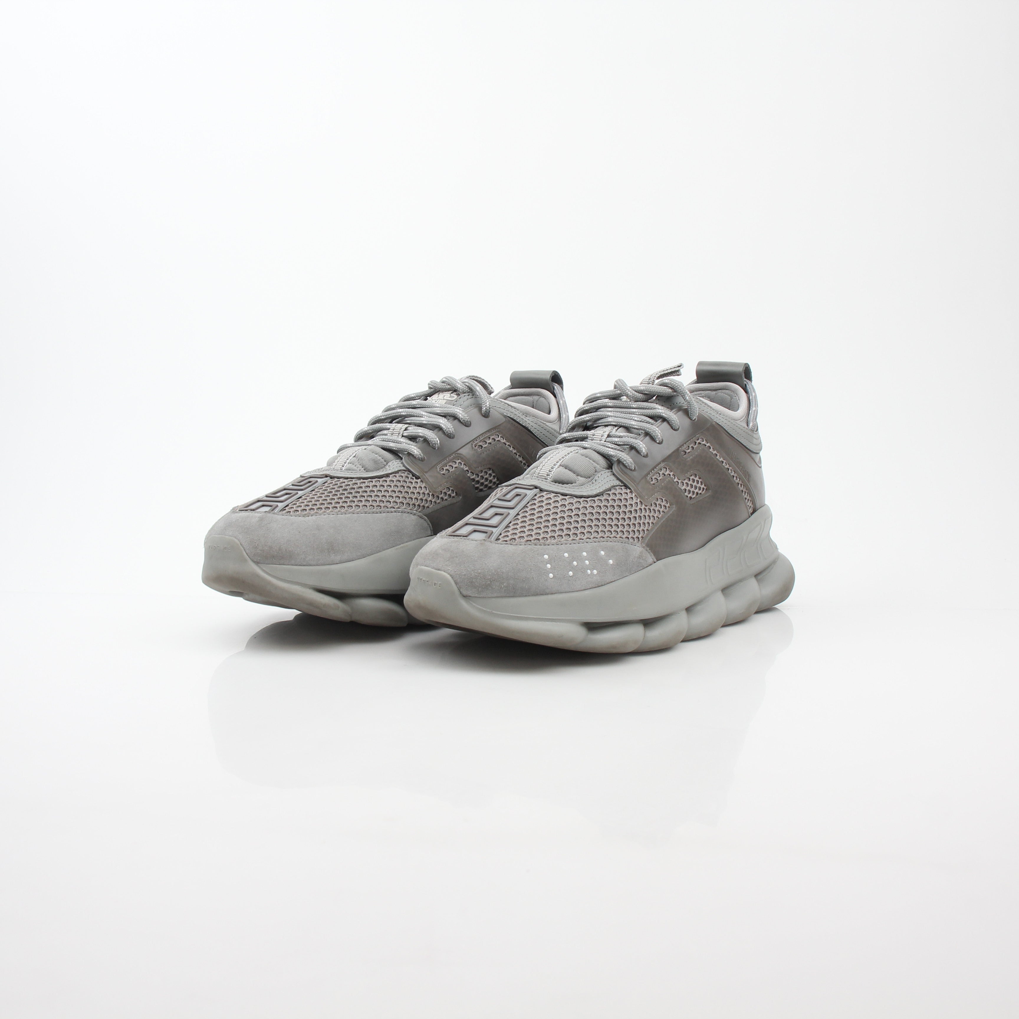 Gray Chain Reaction sneakers by Versace featuring stylish design, white soles, and gray laces on a clean background.