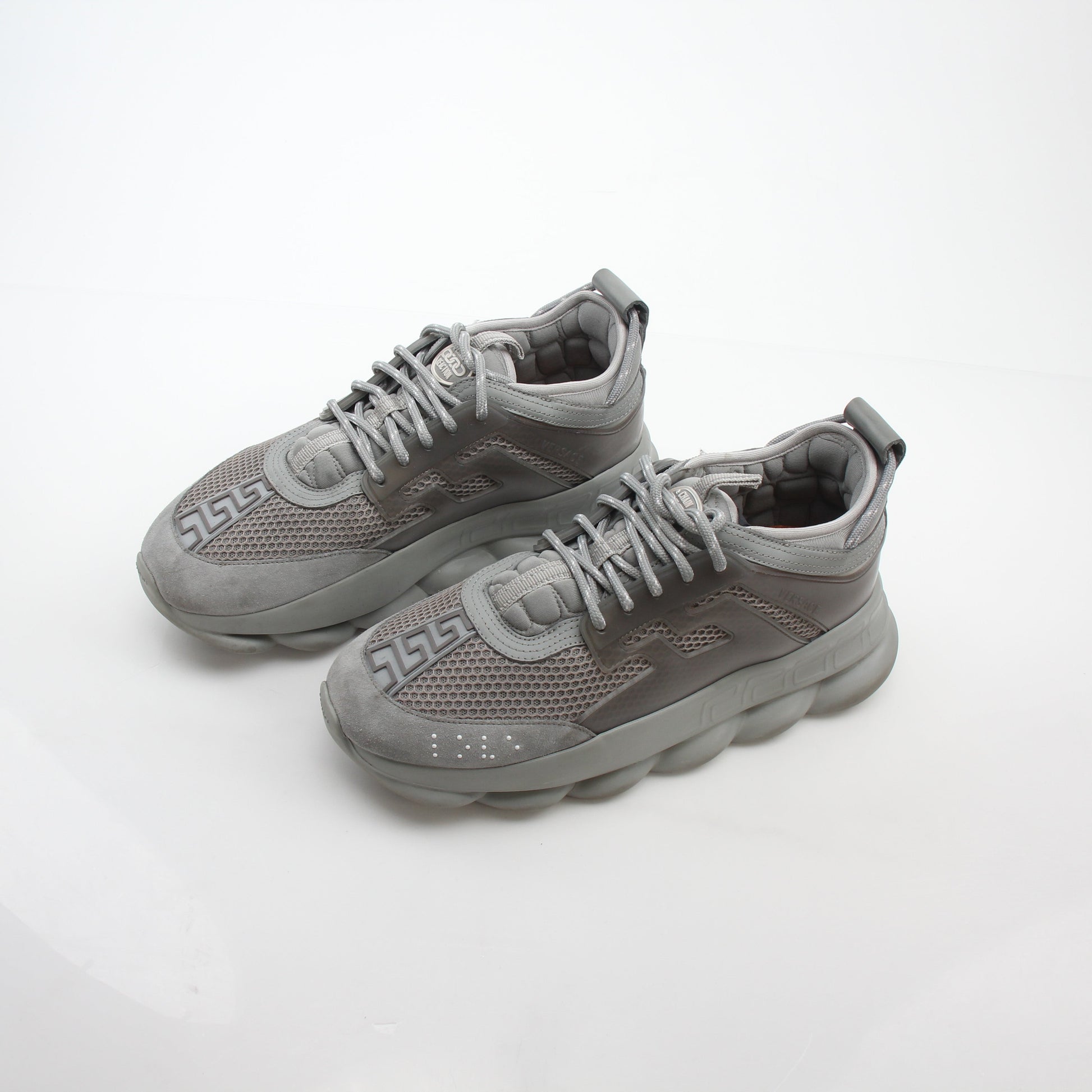 Gray Chain Reaction sneakers by Versace featuring gold accents and a sleek athletic design, shown on a white background.