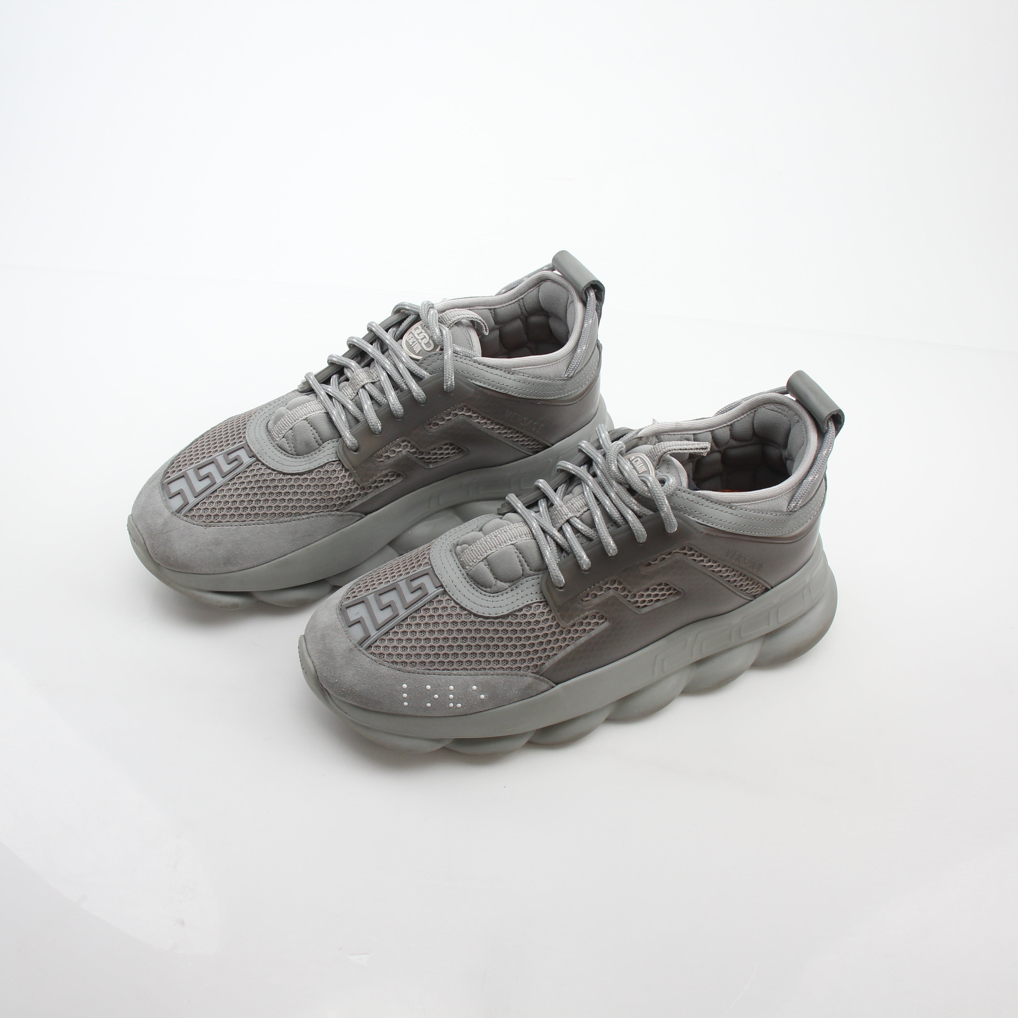 Gray Chain Reaction sneakers by Versace featuring gold accents and a sleek athletic design, shown on a white background.