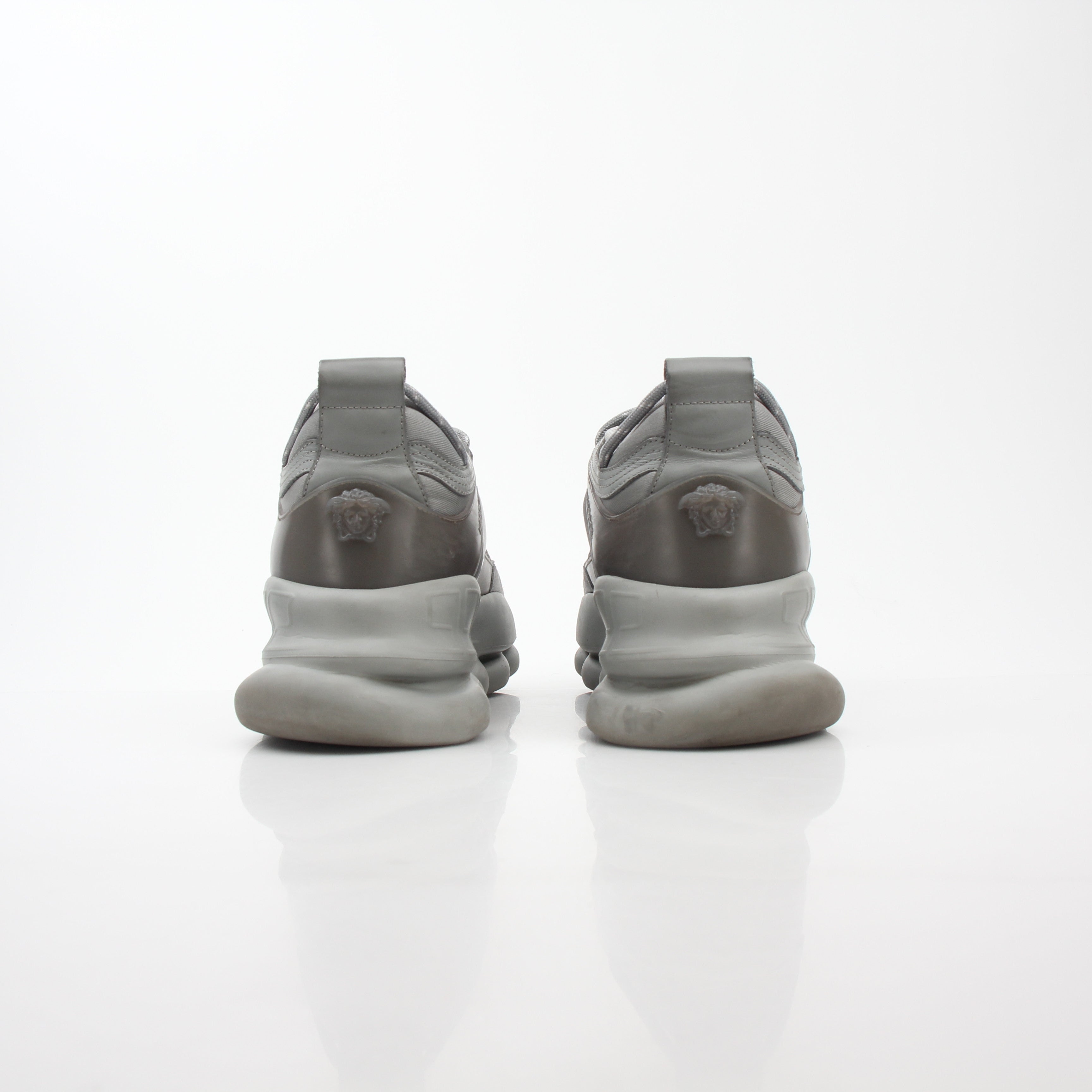 Gray Chain Reaction sneakers by Versace featuring stylish design and gold accents, placed on a white background.