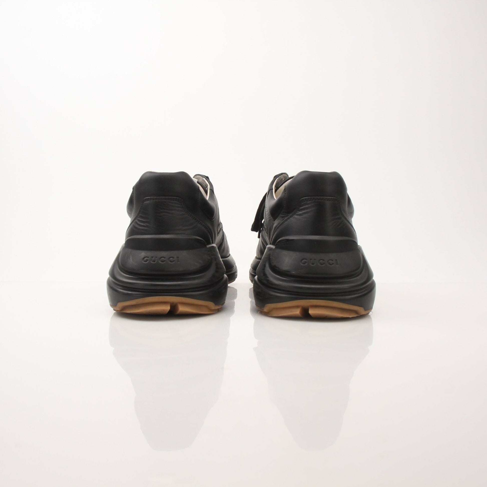 Iridescent Gucci men's Rython logo sneakers with sleek design and white rubber soles, displayed on a neutral background.